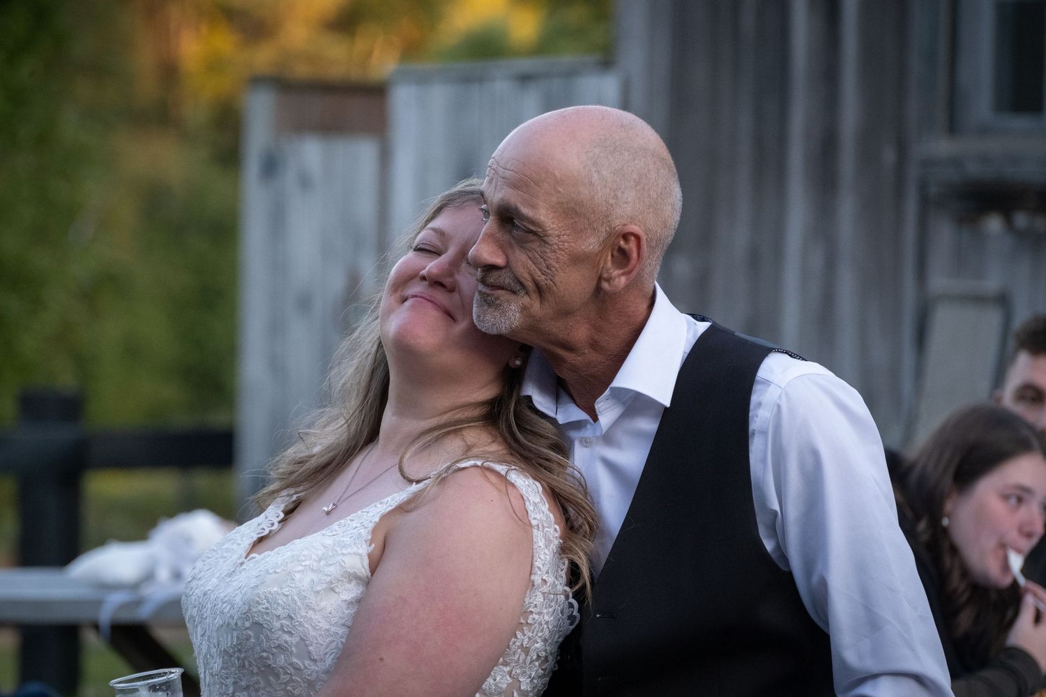 Joyful wedding couple sharing a candid moment during outdoor reception.