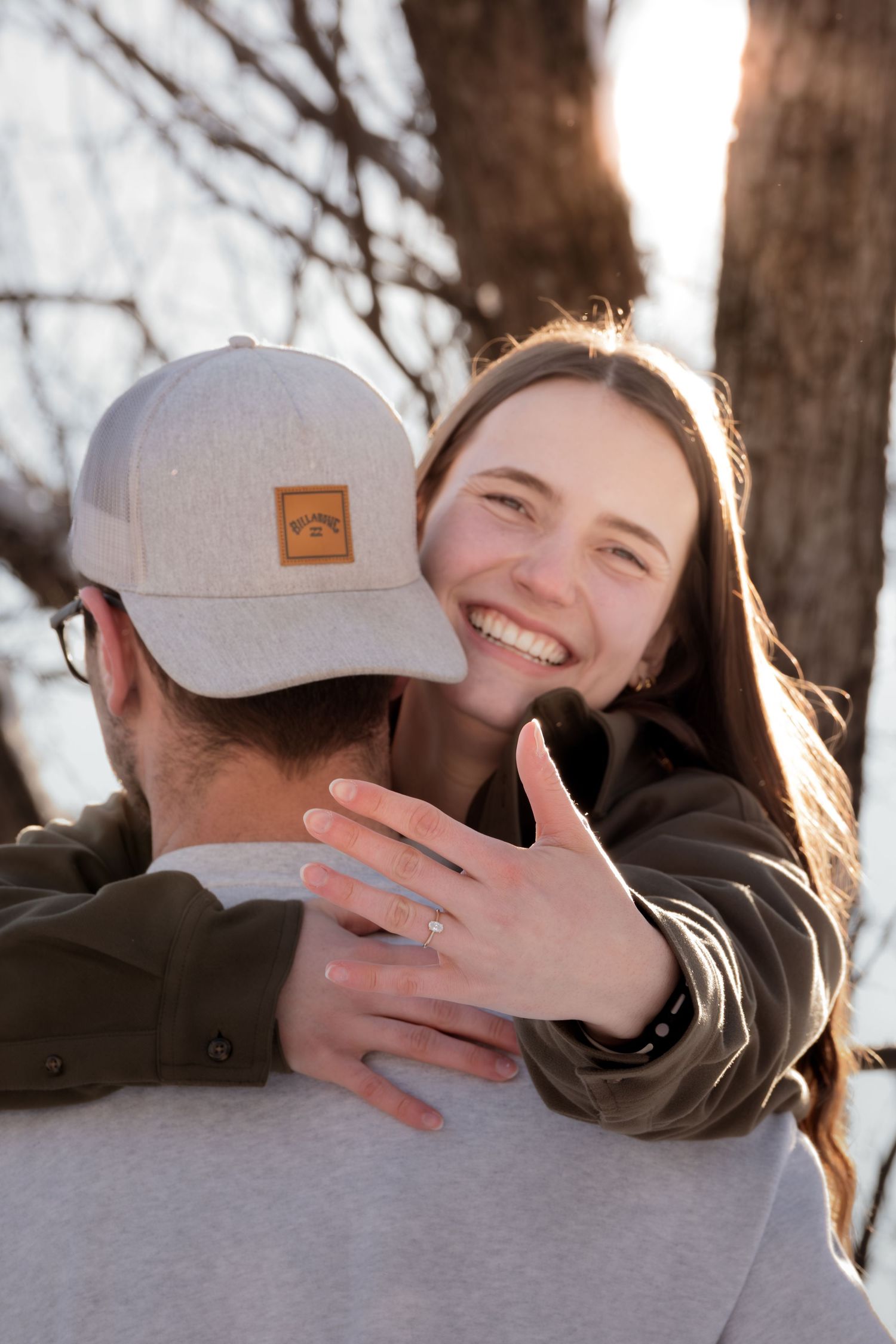 A series of four candid photos showing a joyful embrace in warm sunlight among trees.