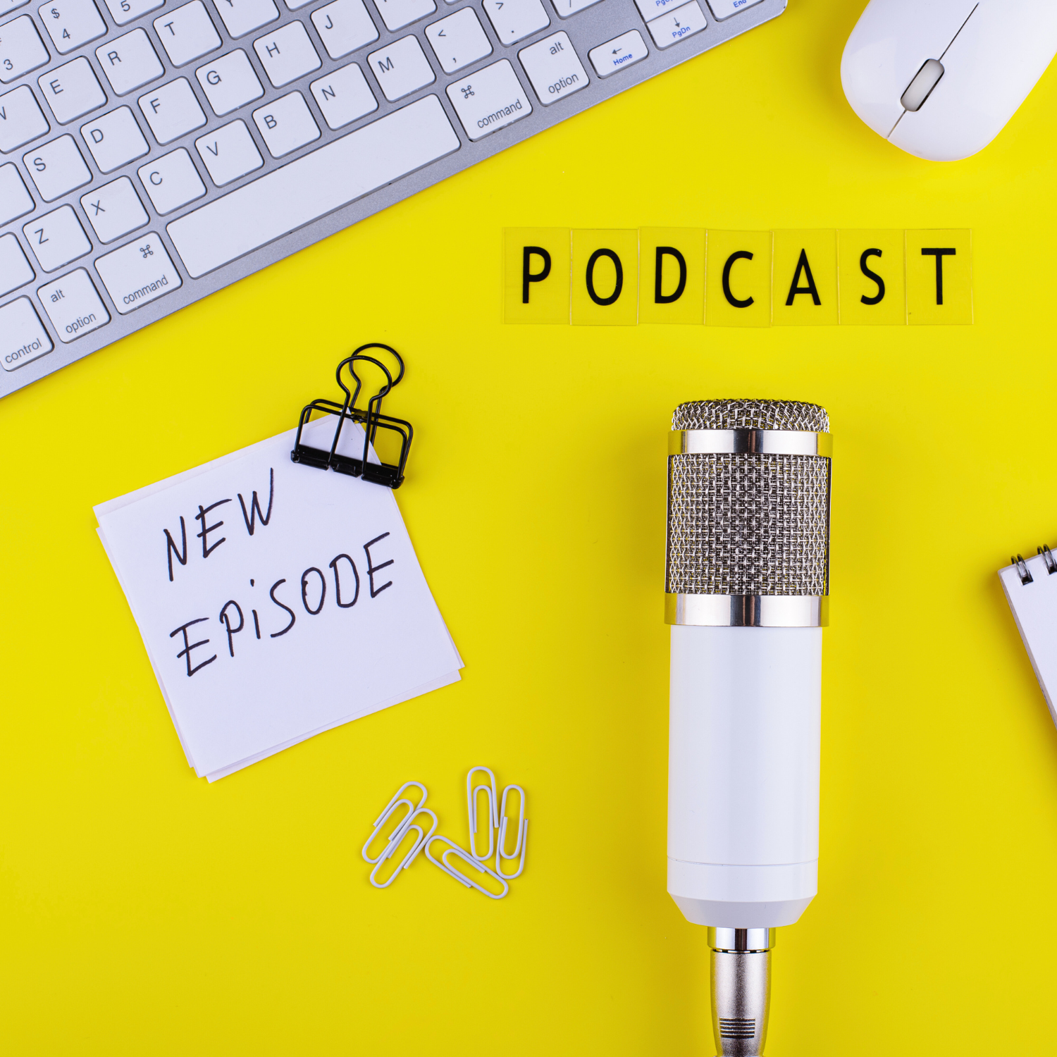 Podcast recording equipment including microphone and keyboard arranged on bright yellow background.