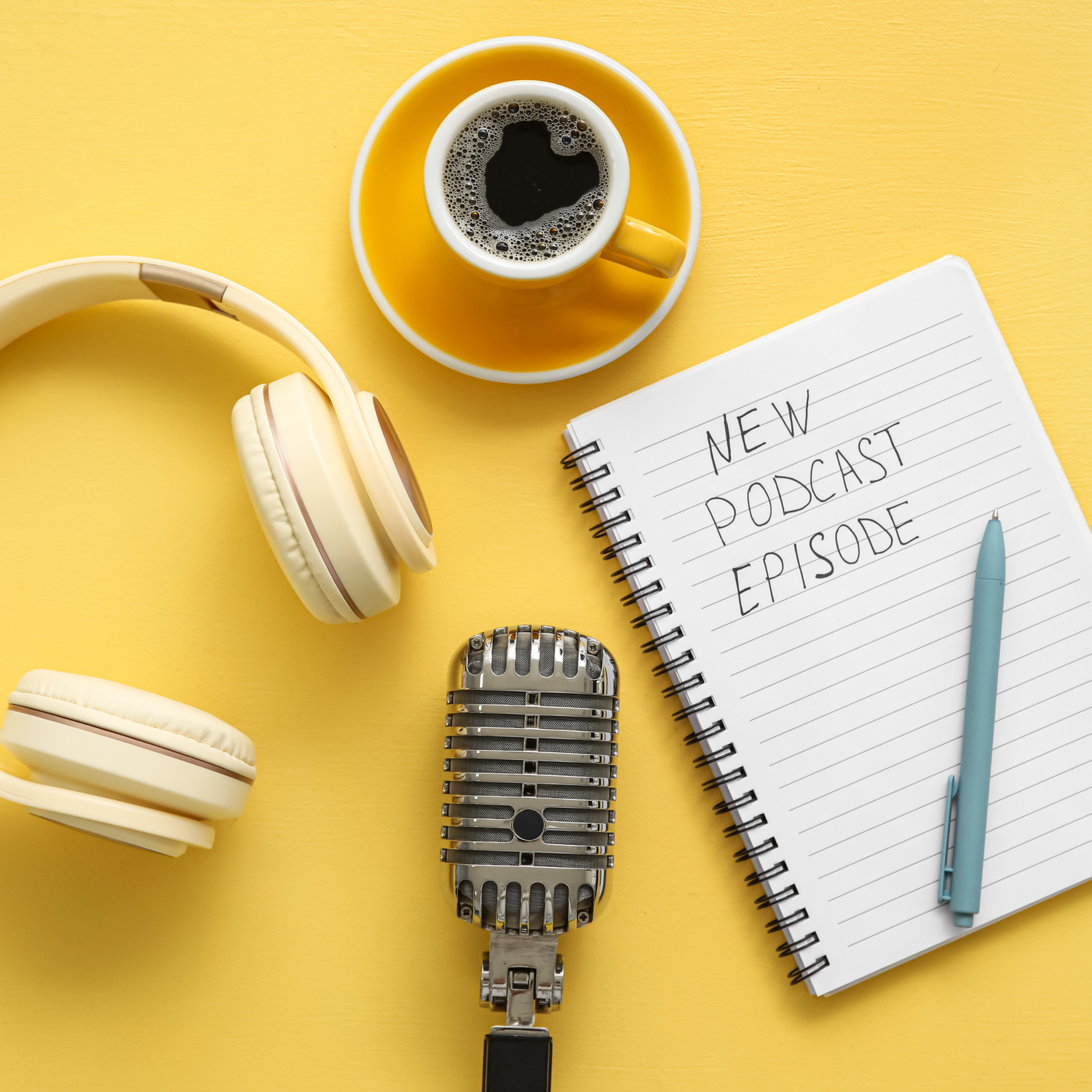 White headphones and coffee cup with notepad on bright yellow background for podcast recording setup.