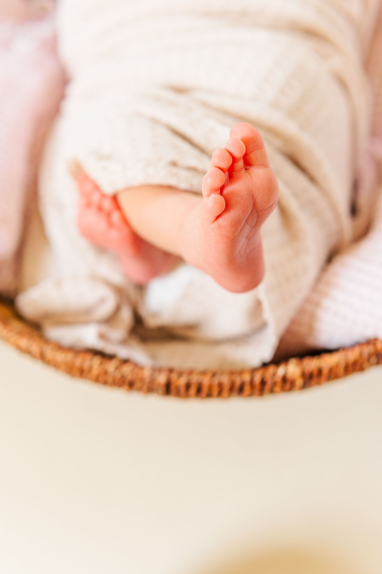 Close-up view of tiny baby feet wrapped in soft white blanket on textured surface.