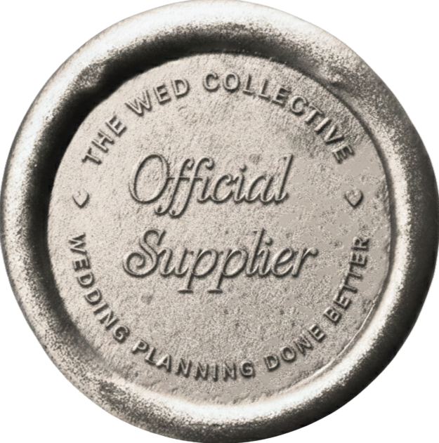 A circular metallic seal or stamp with embossed text reading 'Official Supplier - The Wed Collective' in vintage style.