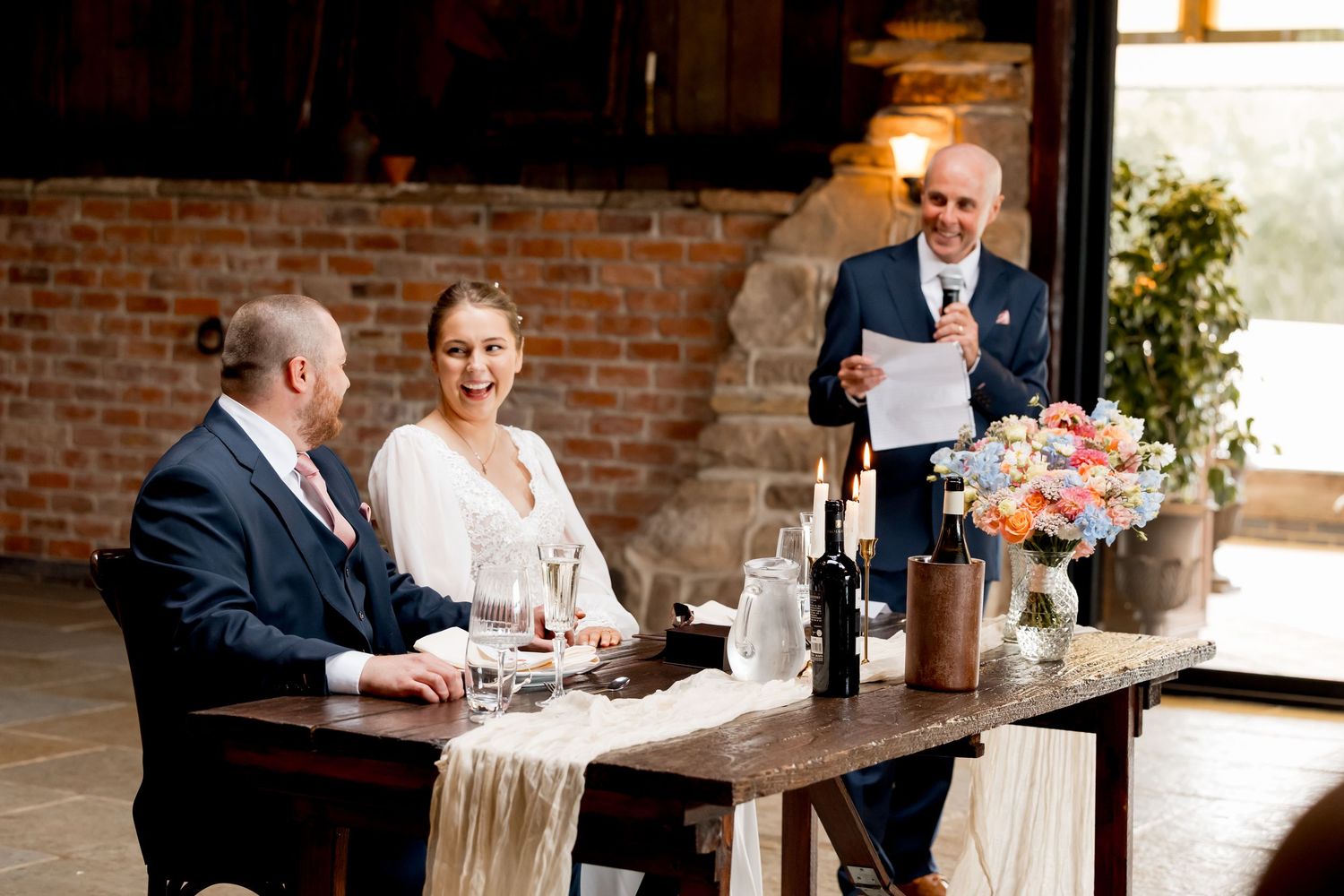Wedding couple sits together at a rustic brick venue during their reception.