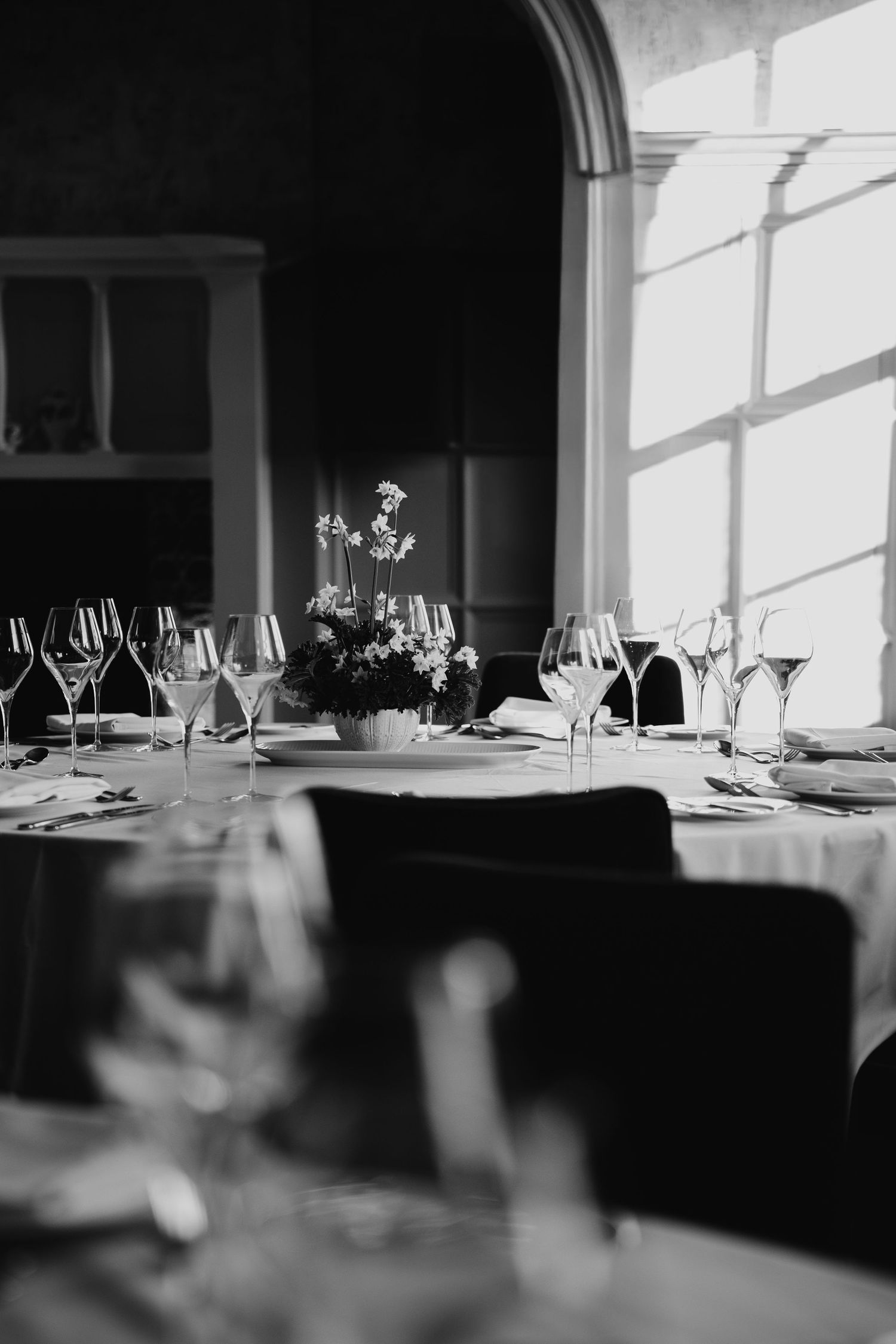 Elegant black and white table setting with wine glasses and floral centerpiece.