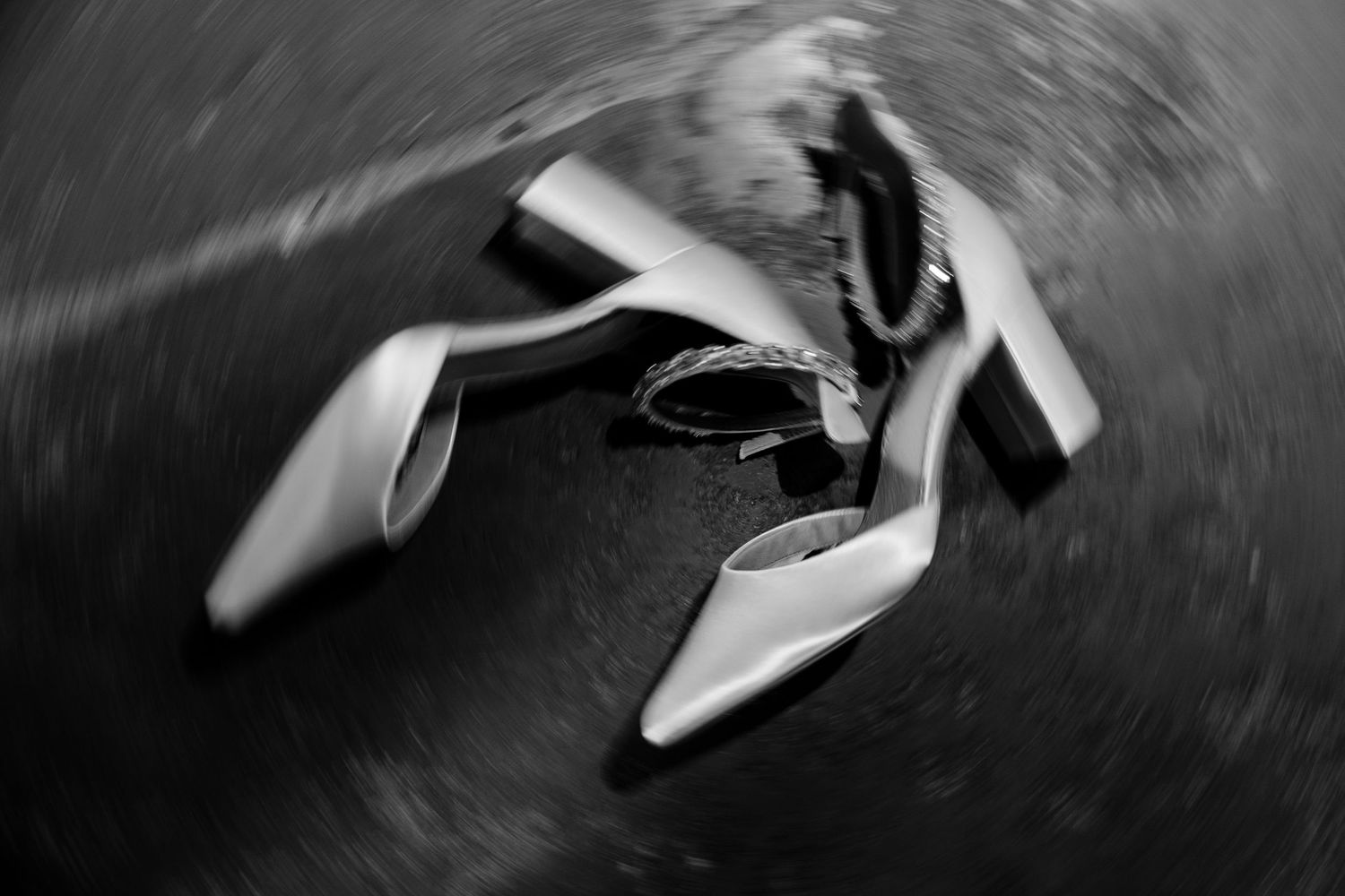 Elegant white bridal shoes arranged artistically in black and white photography.