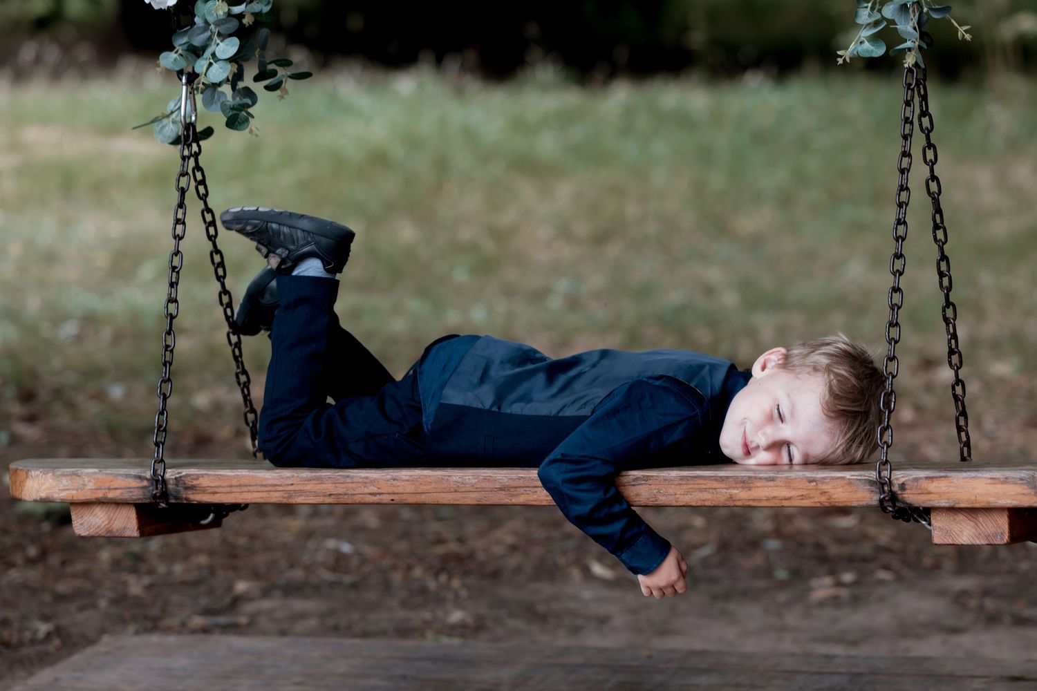 Person lying playfully on outdoor swing set during wedding celebration.