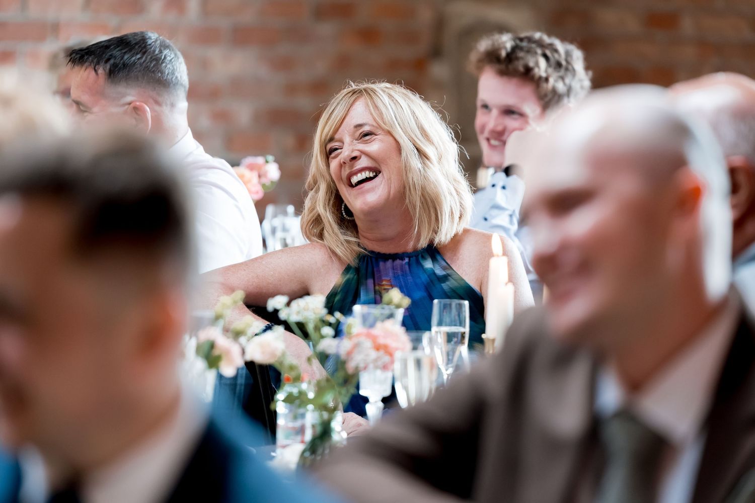 Wedding reception guests sharing joyful laughter at tables.