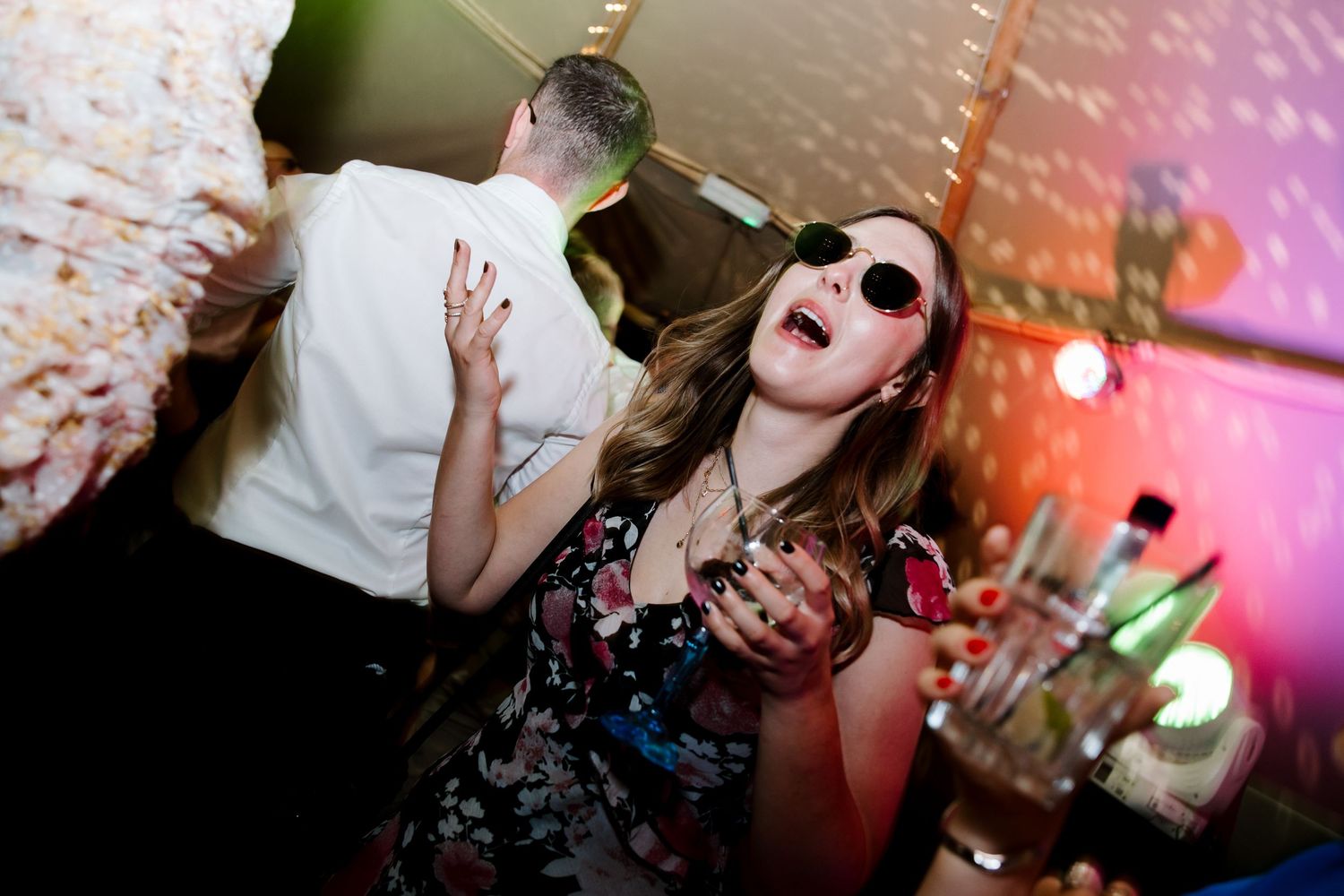 Energetic dance floor scene with party guests celebrating under colorful lighting effects.