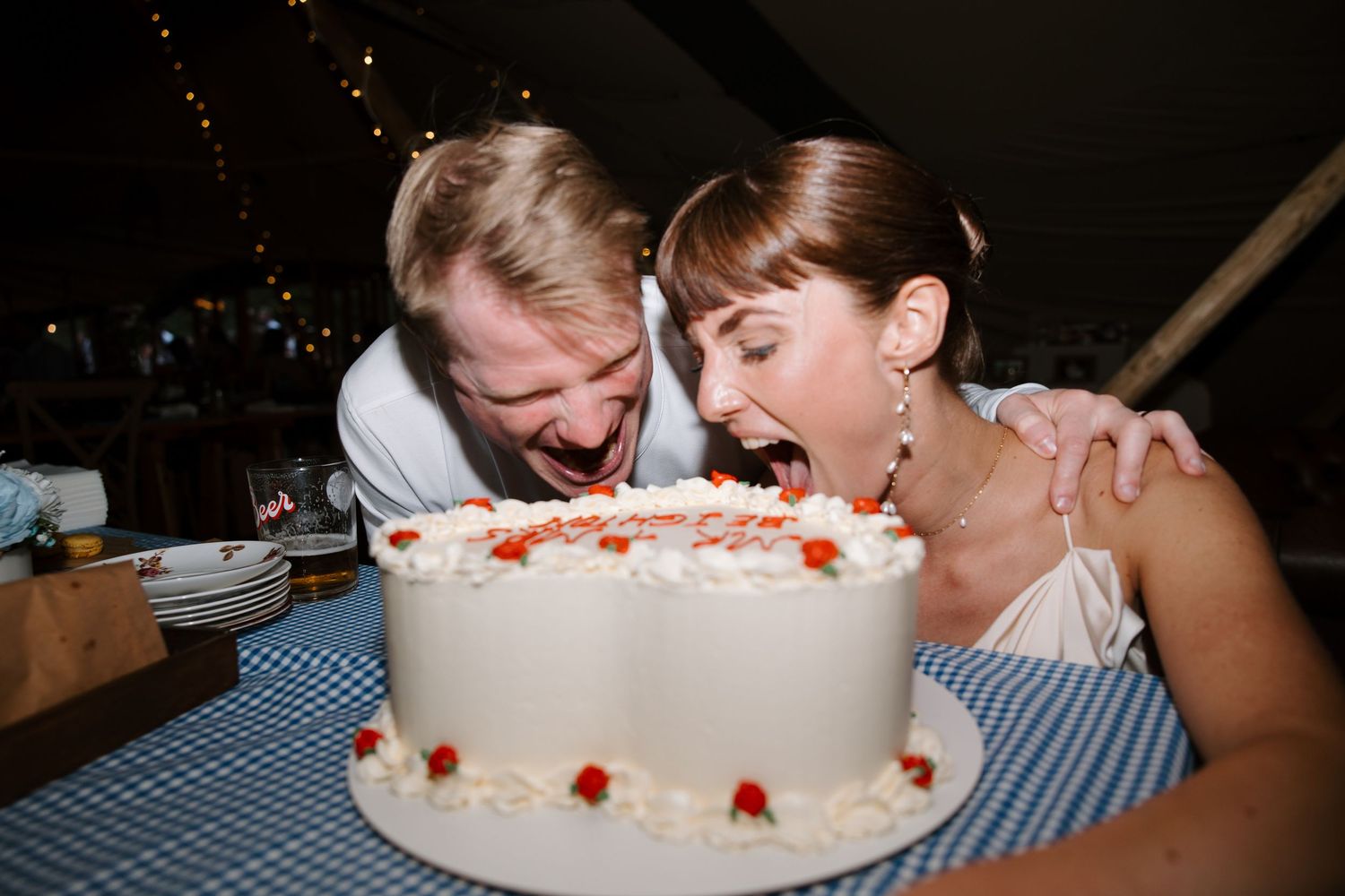Guests enjoying cake and desserts at a reception with checkered tablecloth.