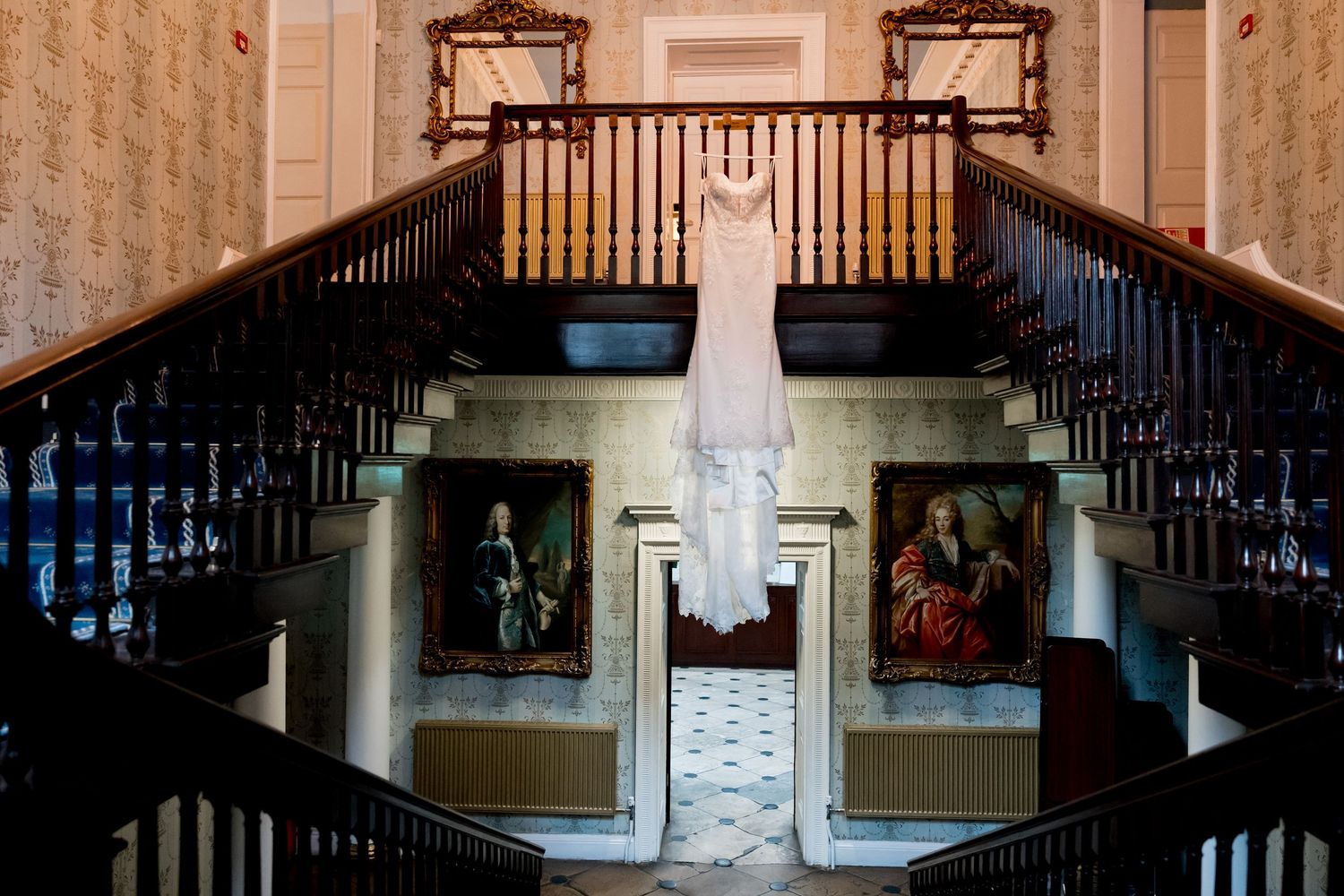 Grand staircase with dark wood railings and white columns in an elegant interior.