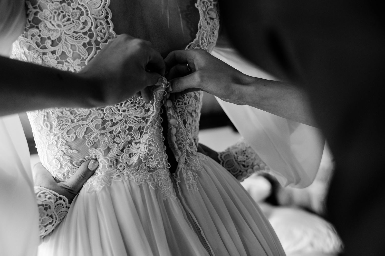 Close-up detail of intricate lace pattern on white wedding dress.