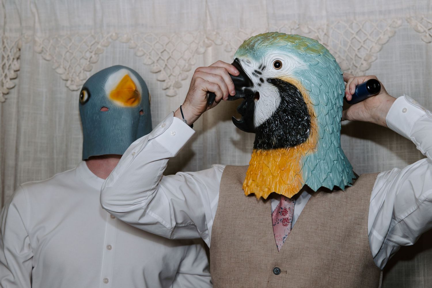 Playful wedding party wearing animal masks and white attire posing together.