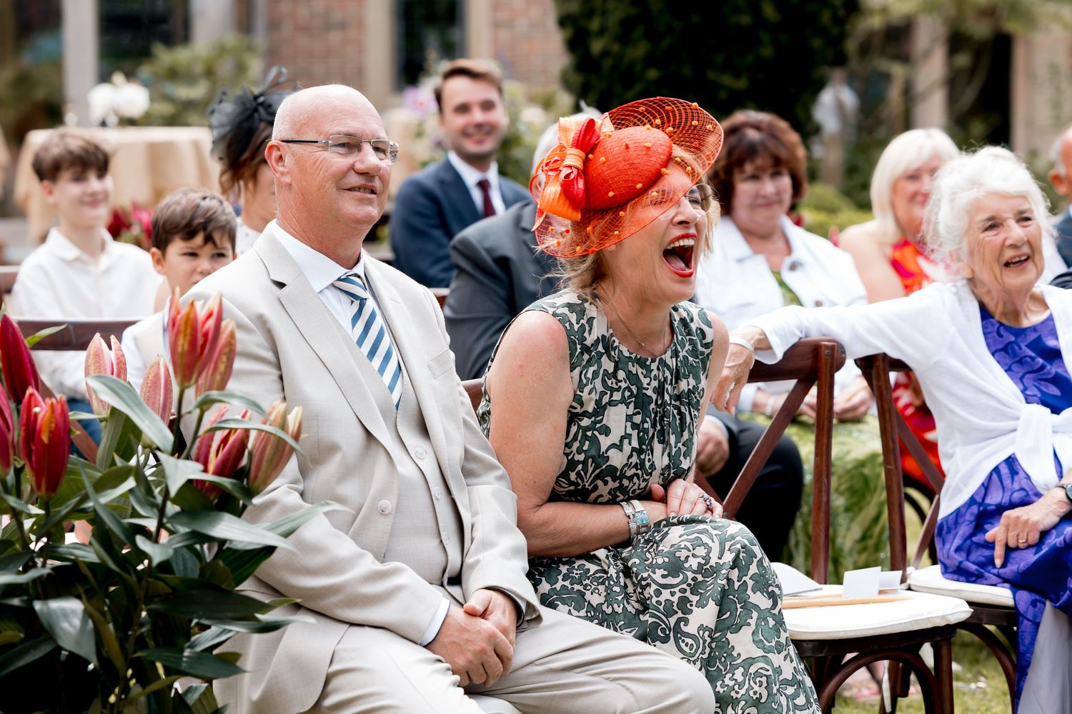 Wedding guests laughing and enjoying themselves during an outdoor ceremony.