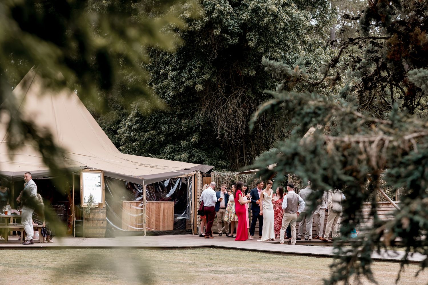 Outdoor wedding venue setup with tents and decorations among trees.