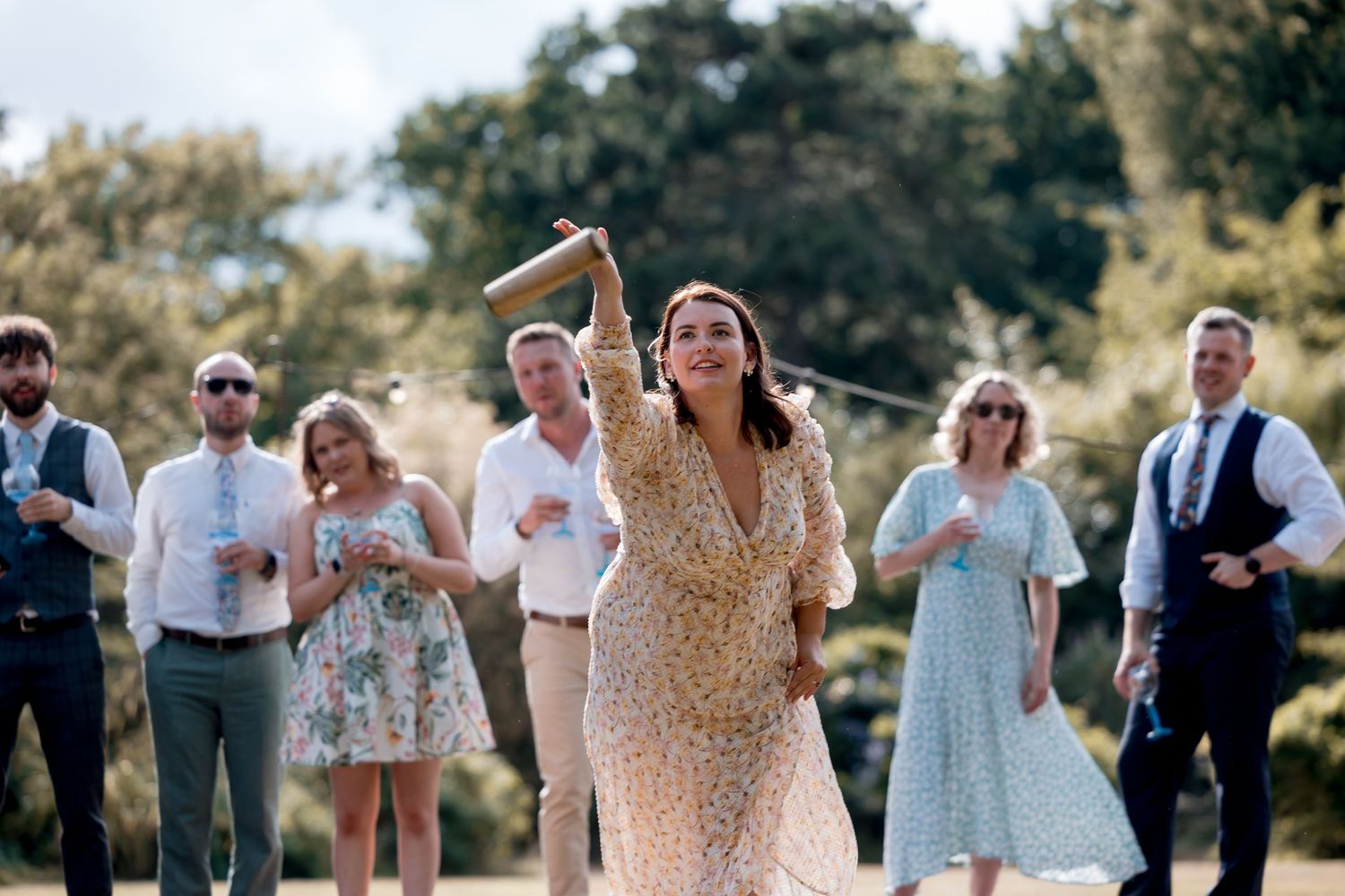Wedding guests in summer attire enjoy an outdoor celebration.