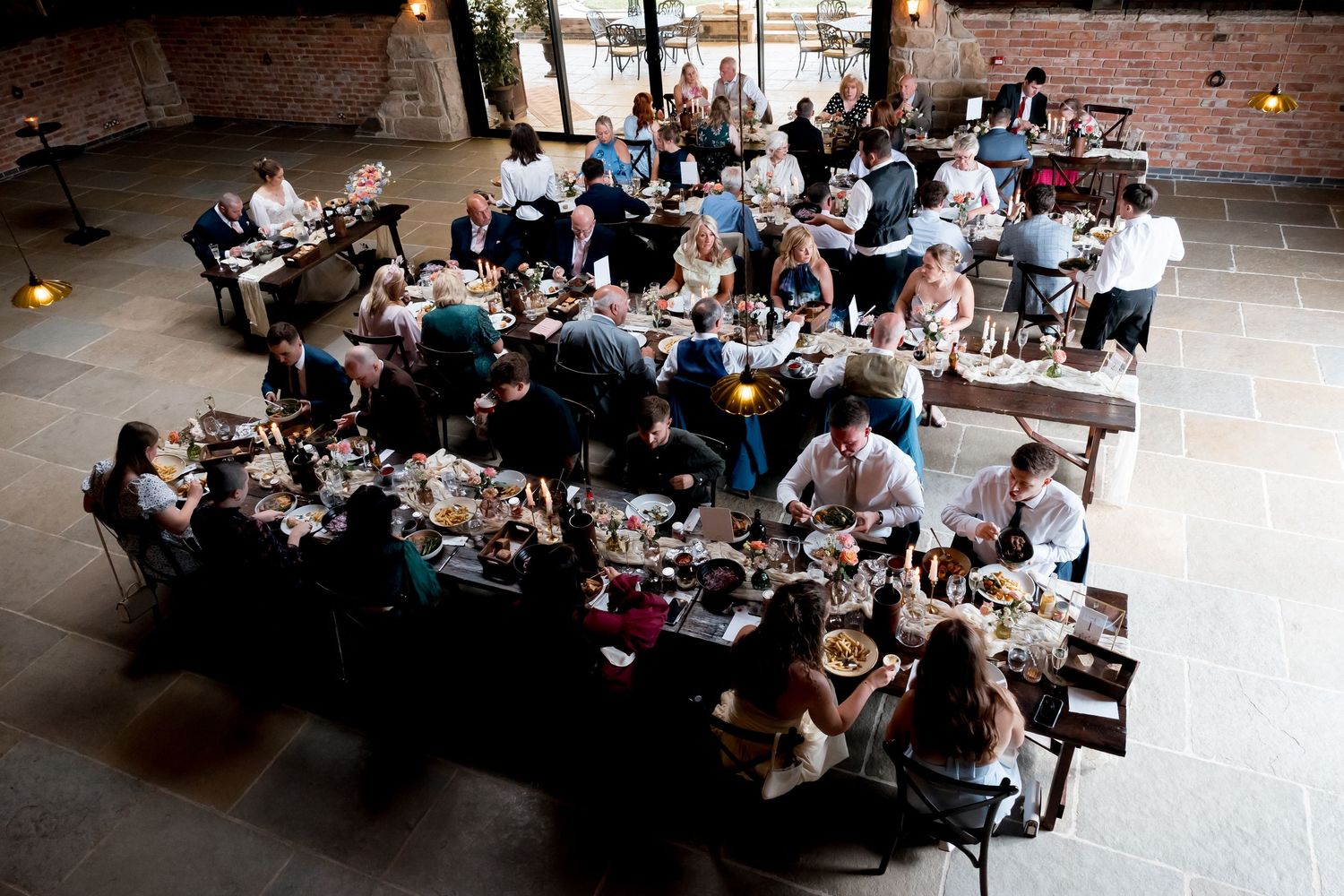 Wide angle view of wedding reception tables filled with guests in an industrial-style venue.