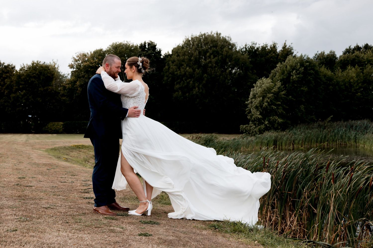 Romantic wedding portraits taken in a natural outdoor setting with cloudy skies.