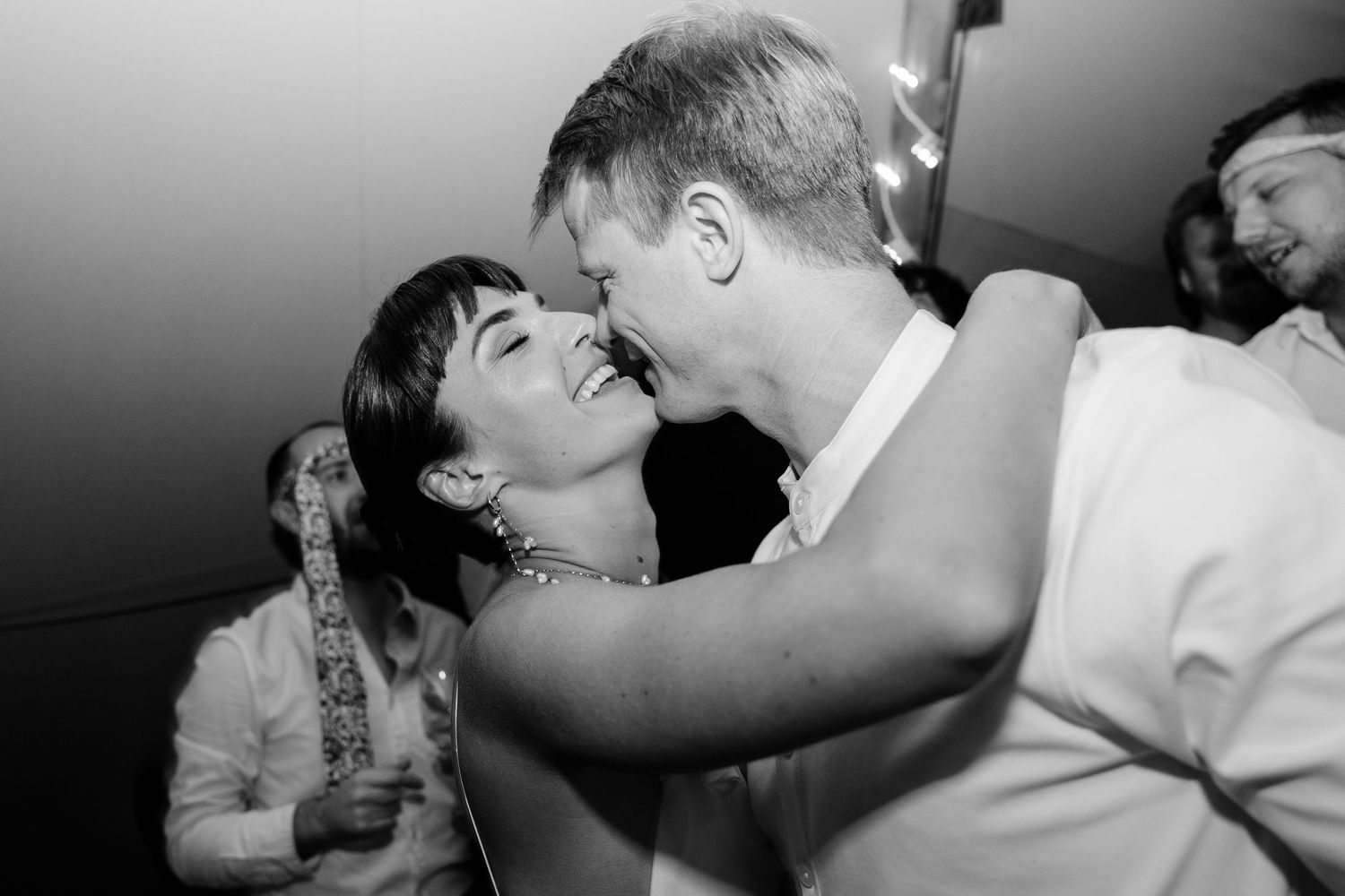 Black and white photo of guests dancing and celebrating at a wedding reception.