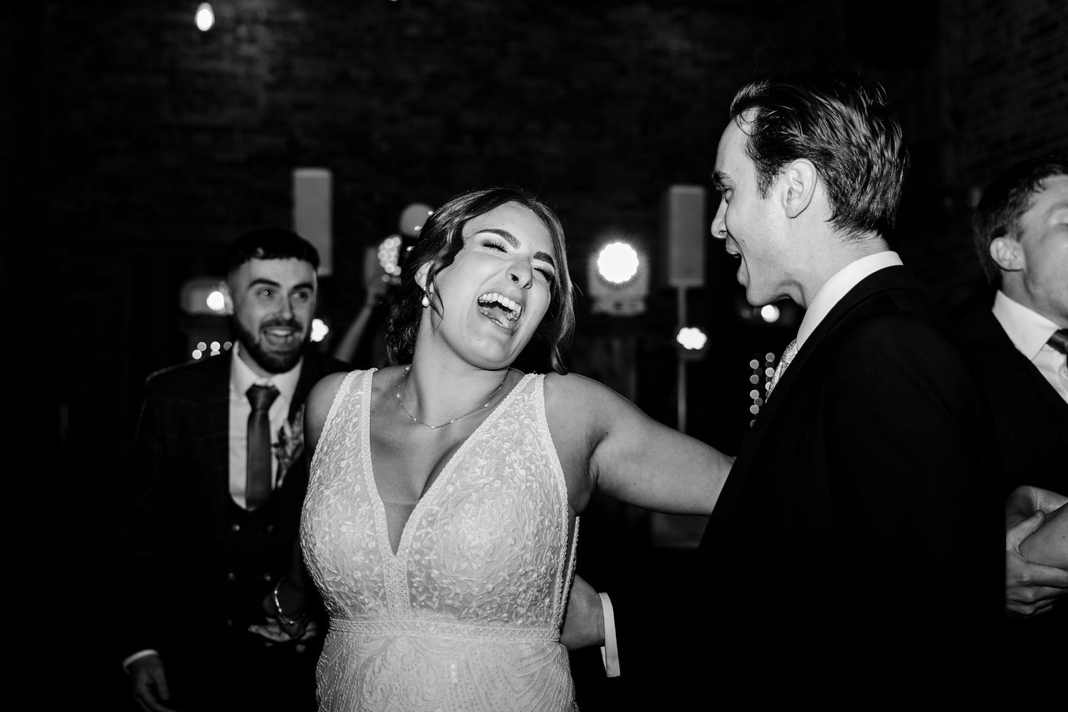 Black and white photo capturing joyful dancing moments at wedding reception.