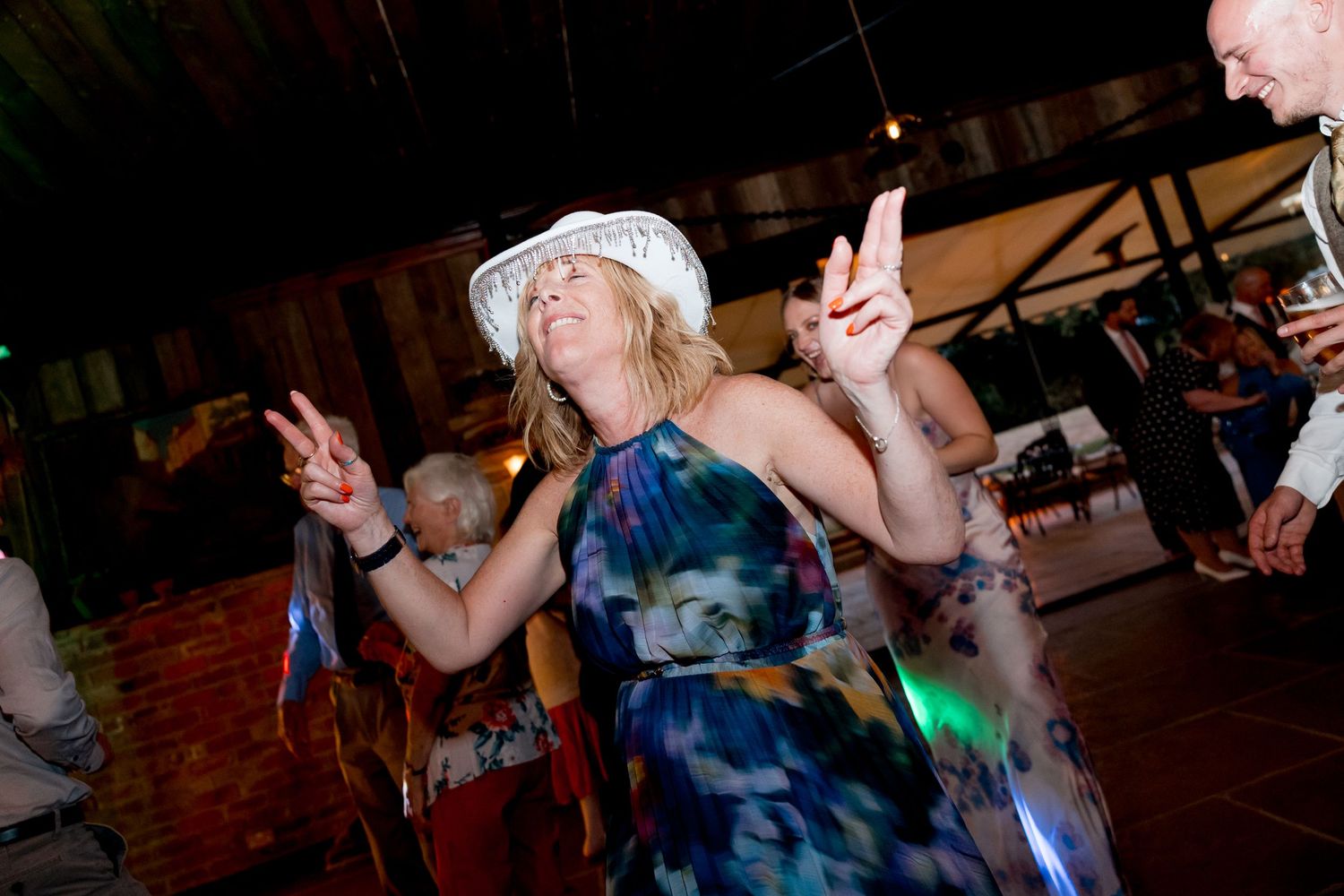 Wedding guests dancing and celebrating on the reception dance floor.
