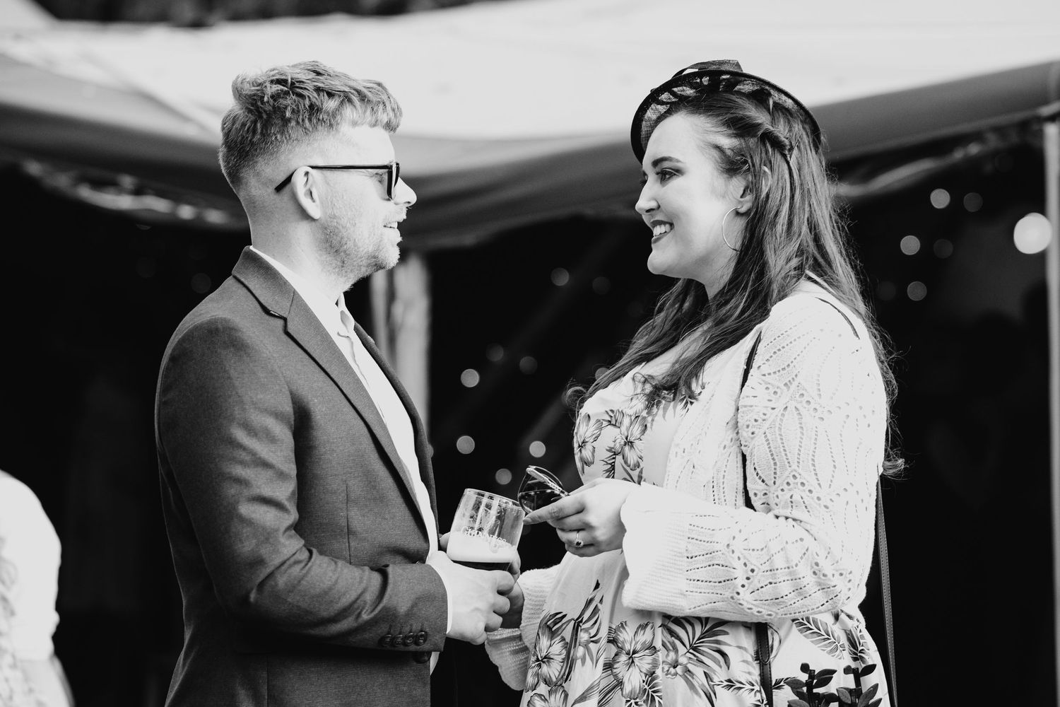 Black and white candid shots of guests laughing and celebrating at an evening reception.