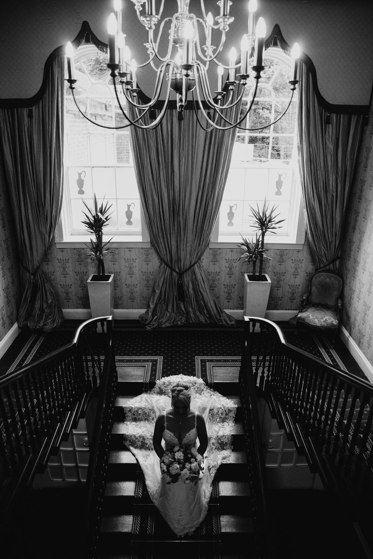 Elegant dining room interior with crystal chandelier and dark curtains in dramatic black and white photography.