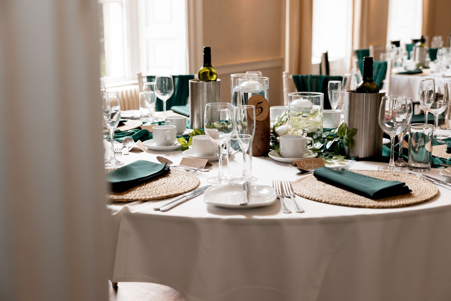 Wedding reception table settings with teal napkins and crystal glassware.