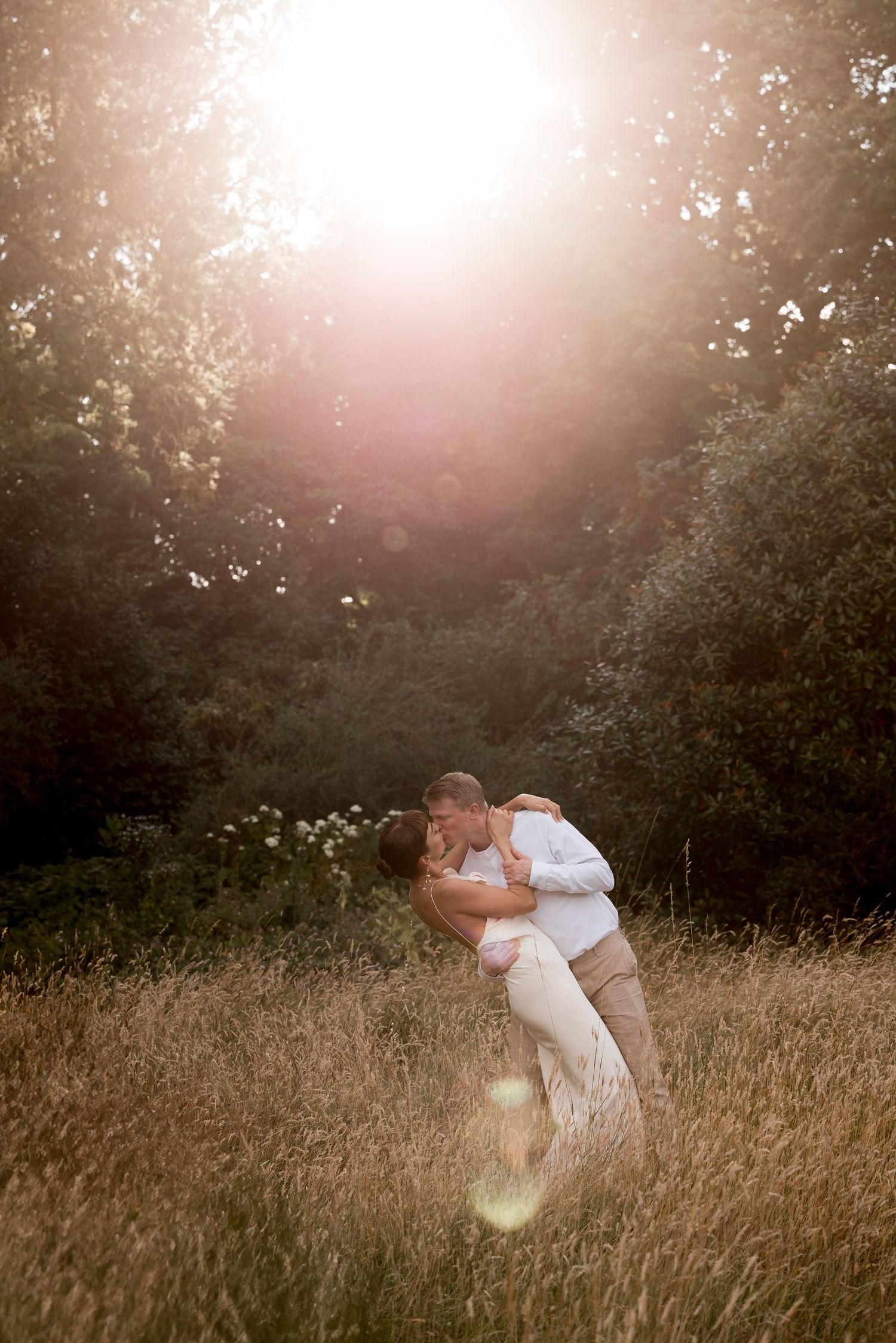 Romantic couple dancing in a sunlit meadow during golden hour.