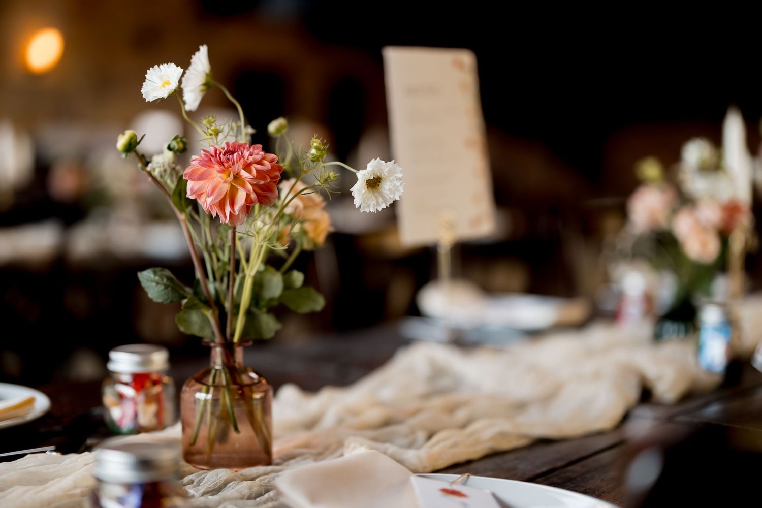 Rustic wedding reception table with floral centerpieces and soft lighting.