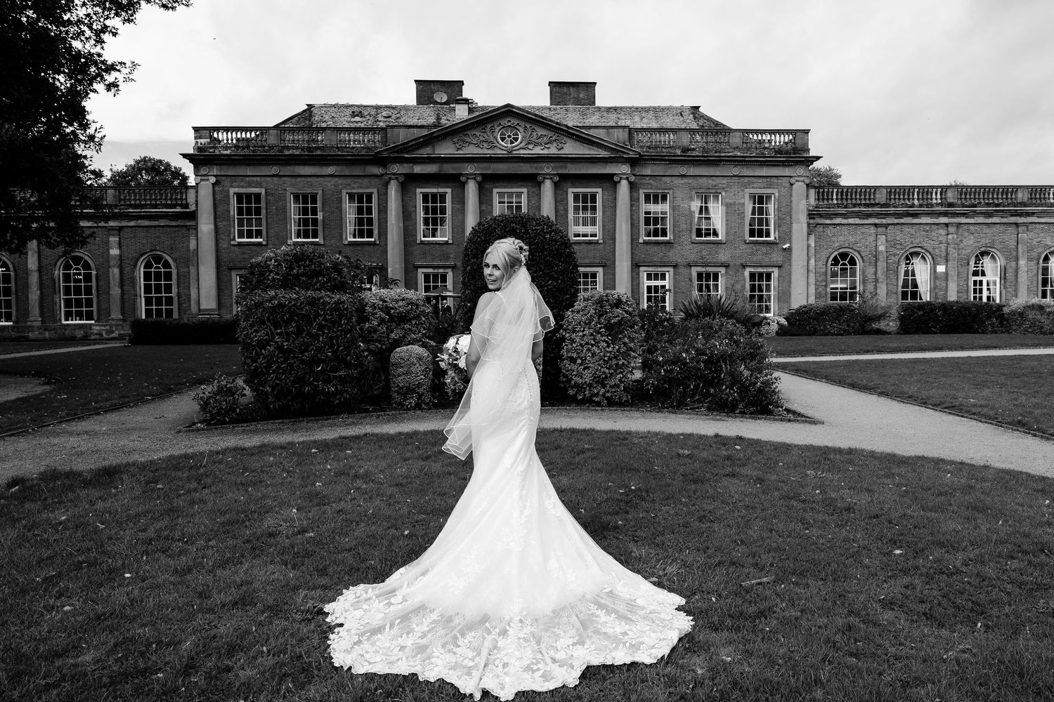 Wedding venue exterior showing historic brick buildings and manicured lawn.