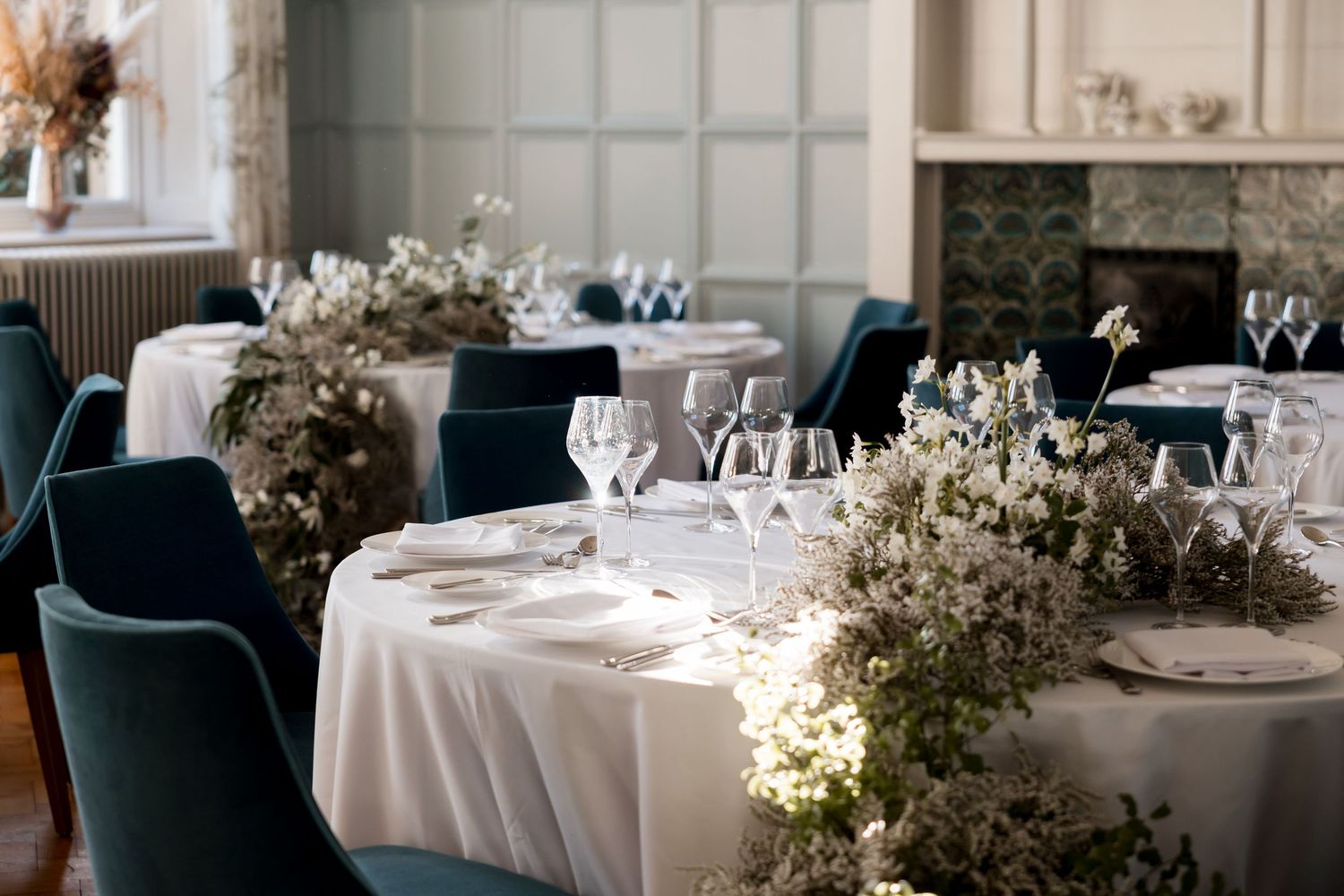 Elegant wedding reception venue with round tables, white linens, and floral centerpieces in a sophisticated dining room.
