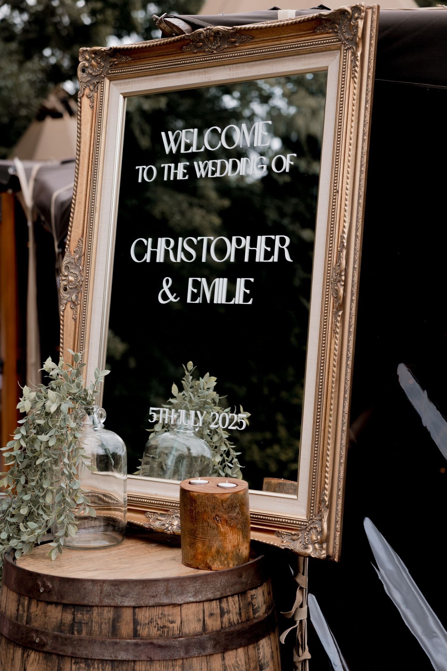 Elegant vintage framed welcome sign for a wedding displayed on rustic wooden barrel.