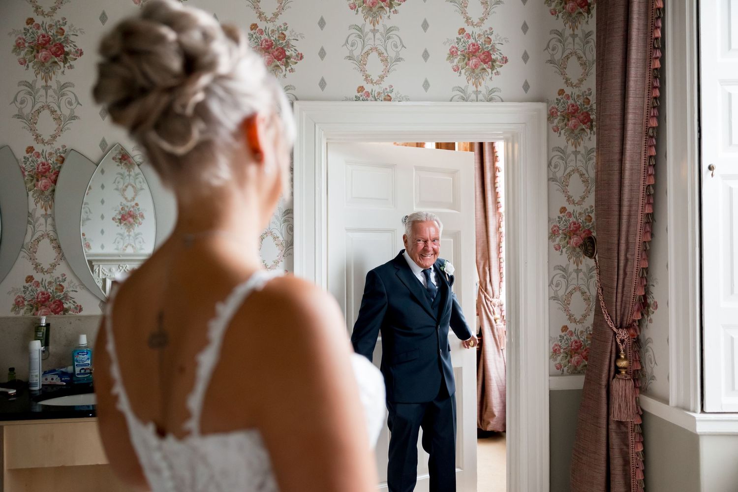 An emotional first look moment captured in a vintage wallpapered room.