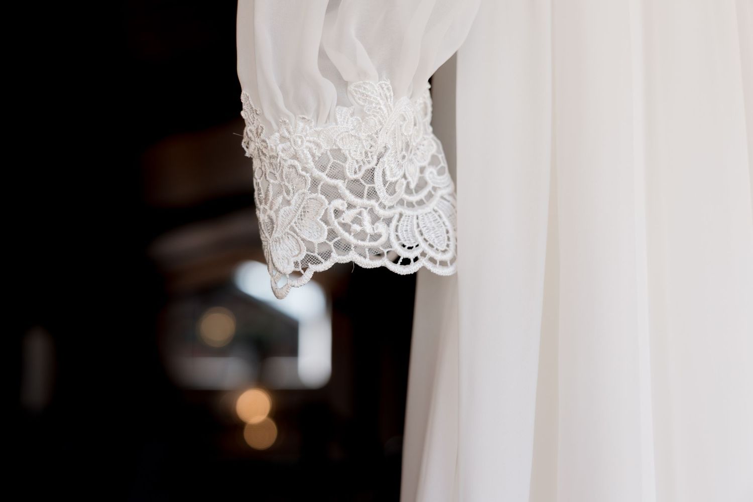 Elegant white lace wedding dress detail showing delicate floral patterns and scalloped edges.