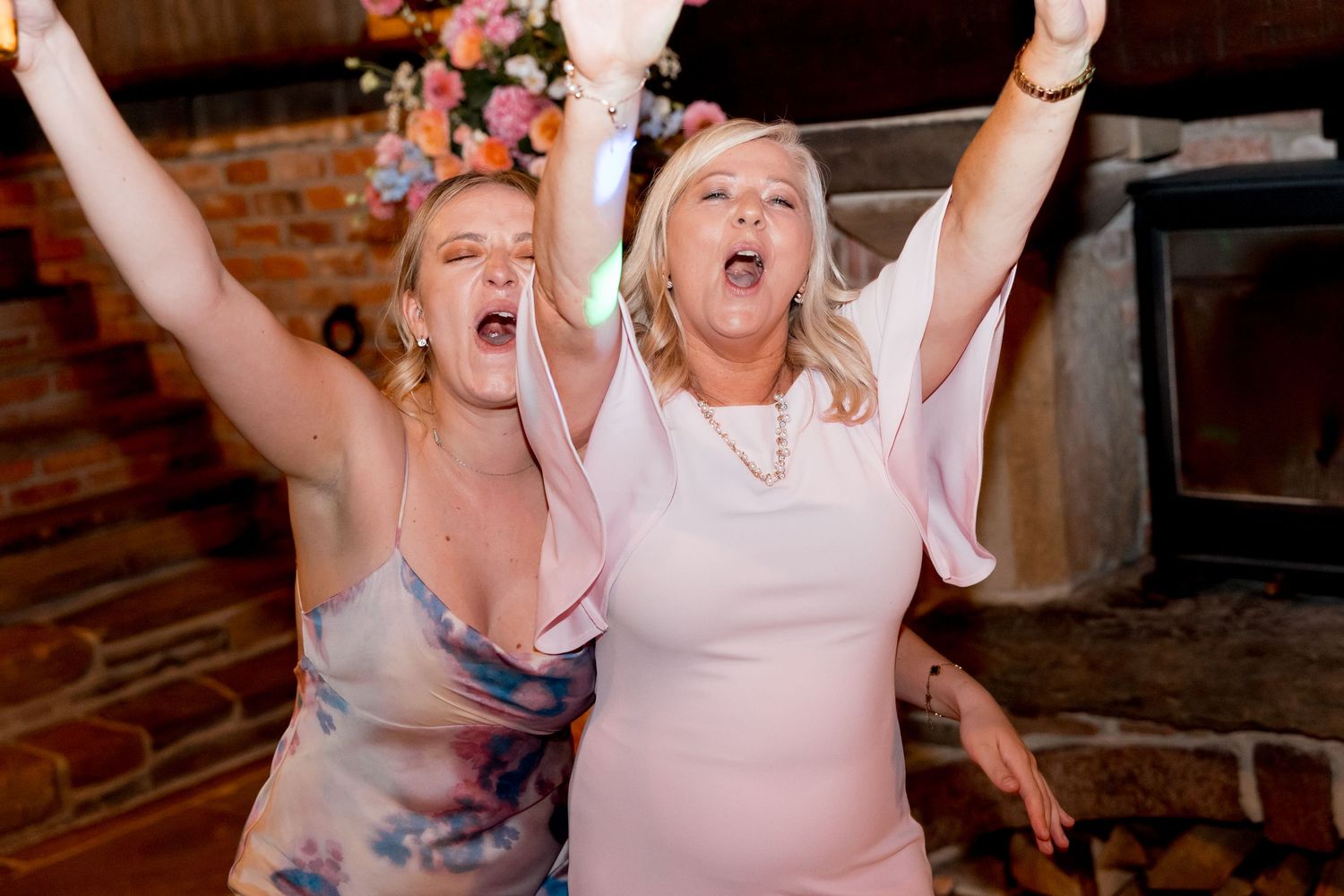Joyful celebration with people dancing and raising their arms in a rustic venue.