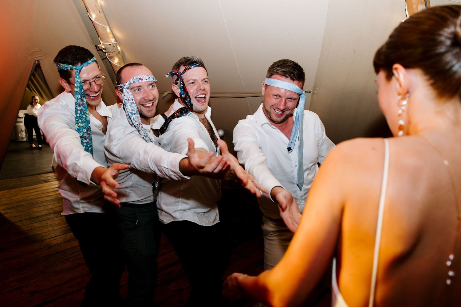 Wedding reception dance party with guests enjoying themselves under warm lighting.