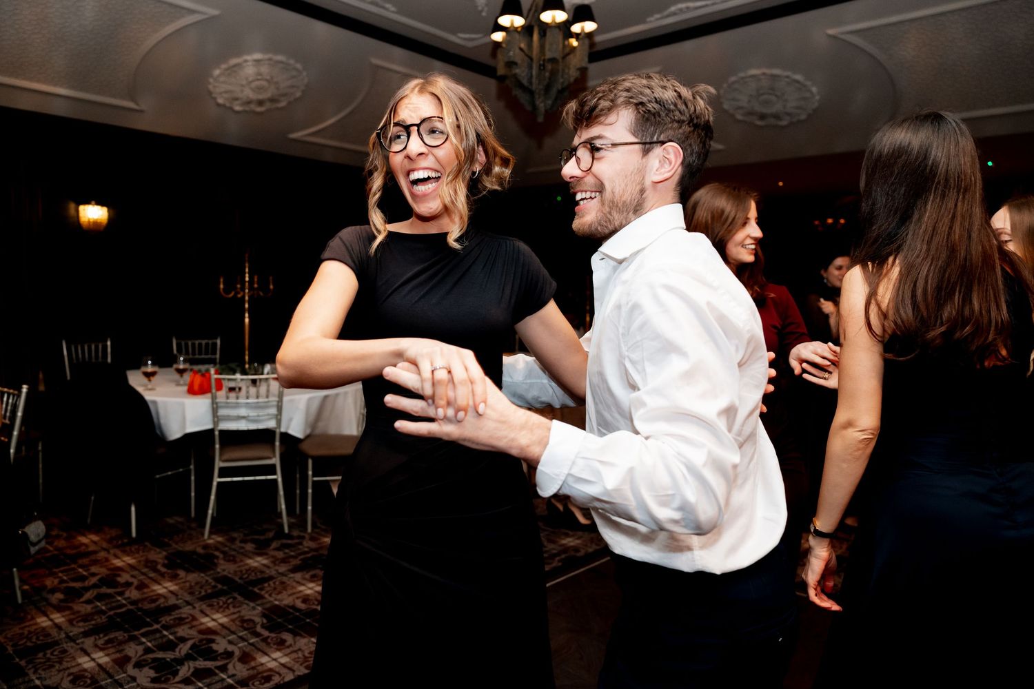 Couple laughing and dancing together joyfully at a wedding reception celebration.