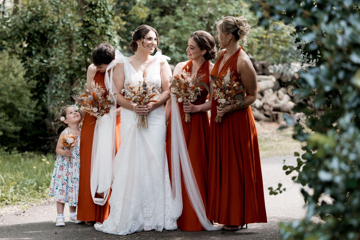 Bridal party in white and burgundy dresses walking together outdoors.