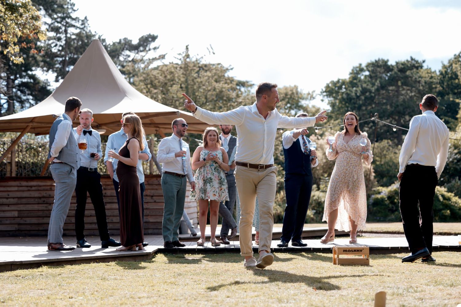 Wedding party and guests line up for group photos outdoors.