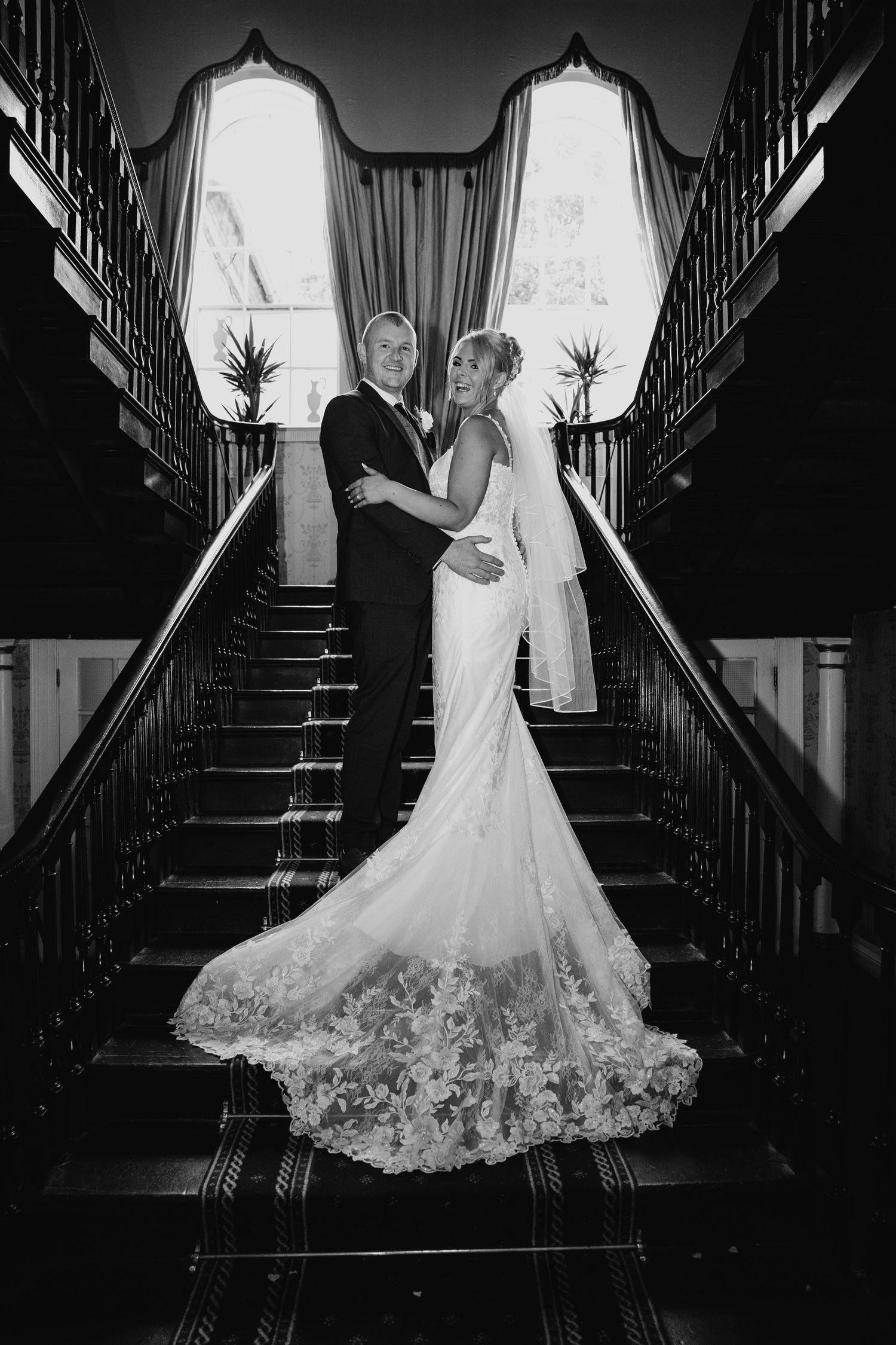 Dramatic black and white staircase portraits showcasing an elegant lace wedding gown.