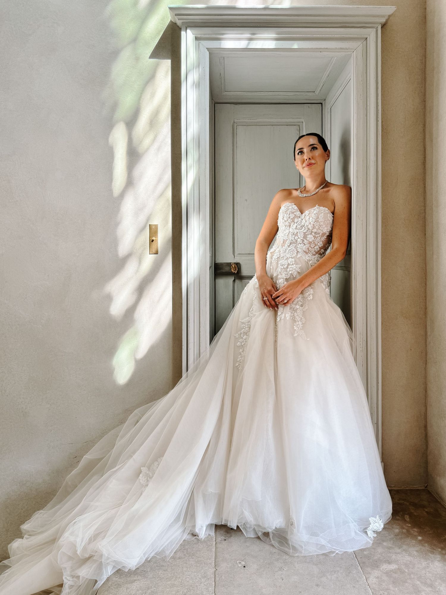 Elegant bridal portraits in a sunlit room showcasing a flowing white wedding gown.