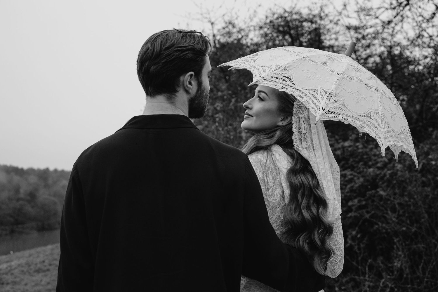 Black and white photo of a couple sharing an intimate moment under a veil outdoors.