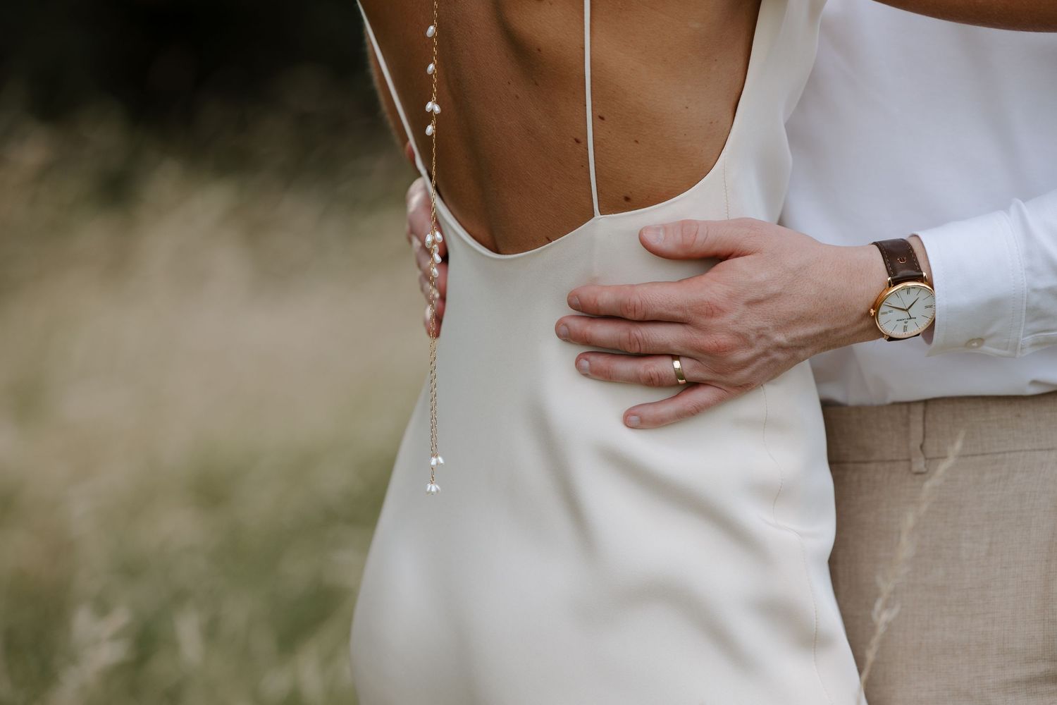 Close-up details of wedding attire and embracing couple outdoors.