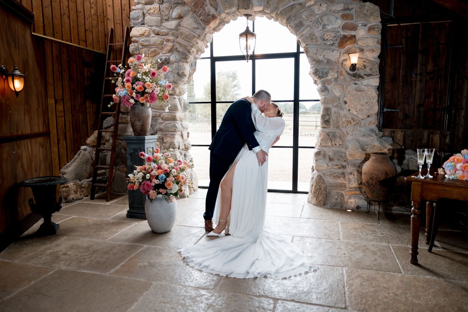 Rustic stone wall wedding venue with large windows and romantic lighting.