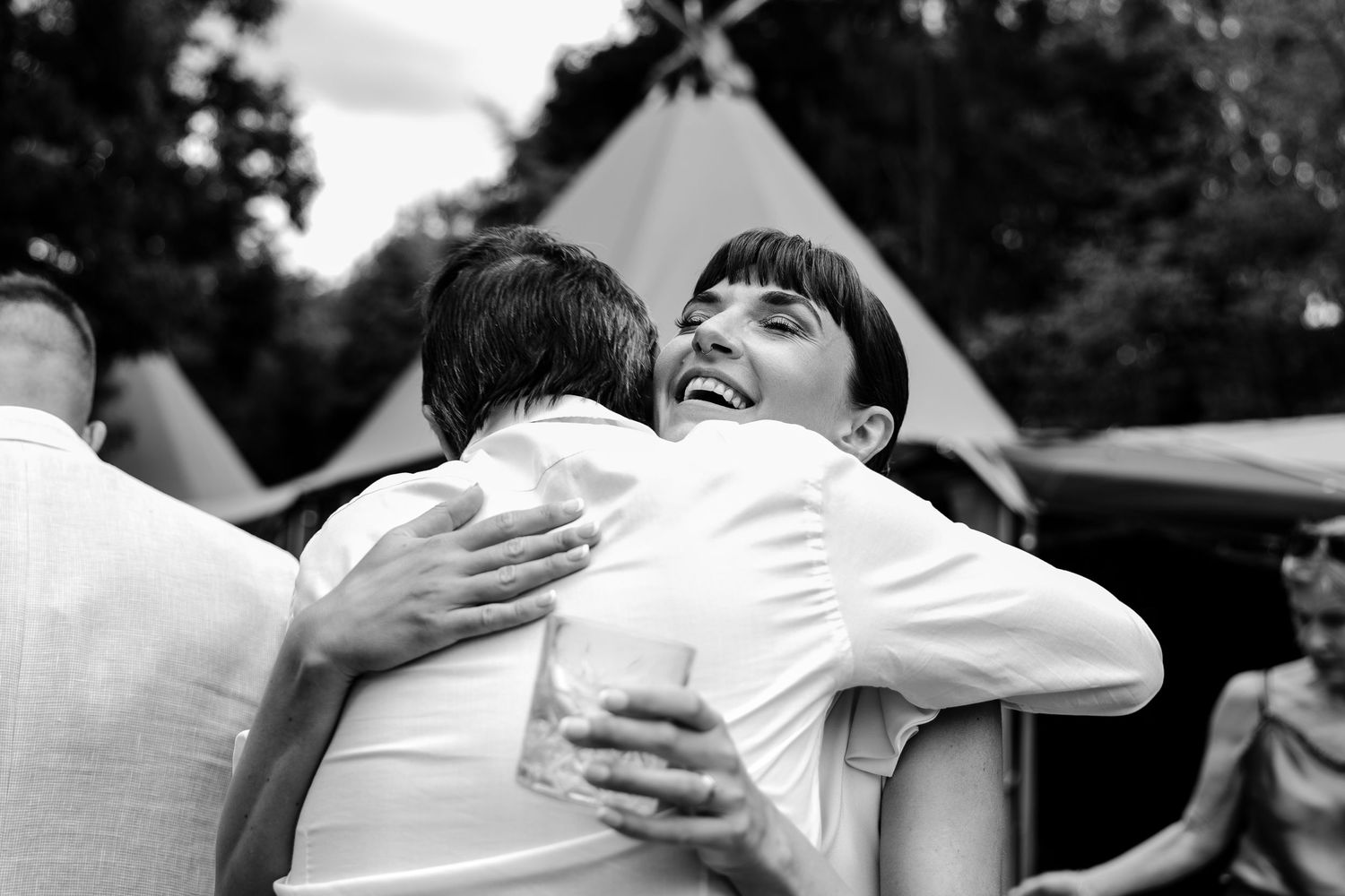 Emotional embraces and candid moments captured at outdoor wedding celebration.