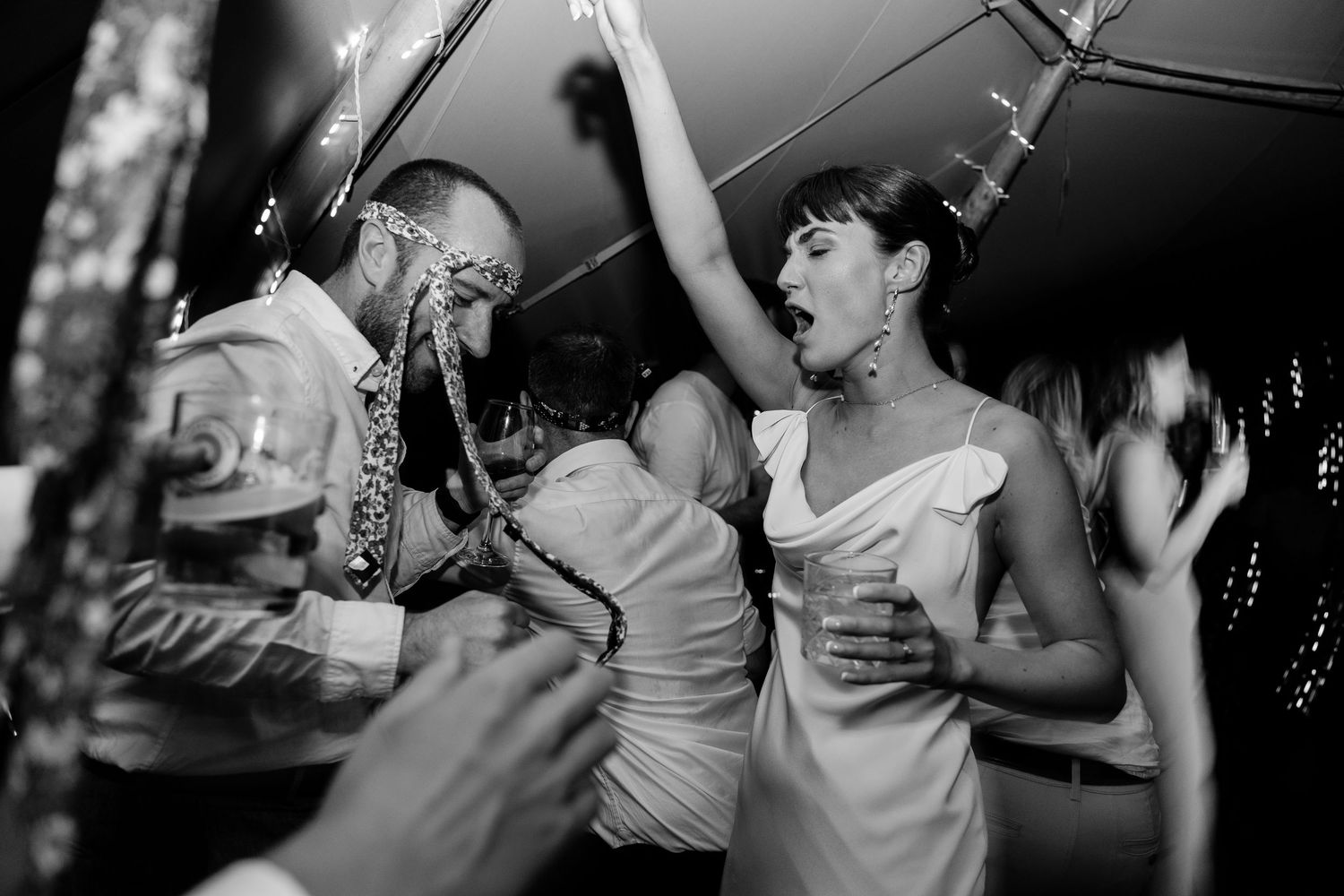 Black and white candid shots of guests dancing and celebrating at a wedding reception.
