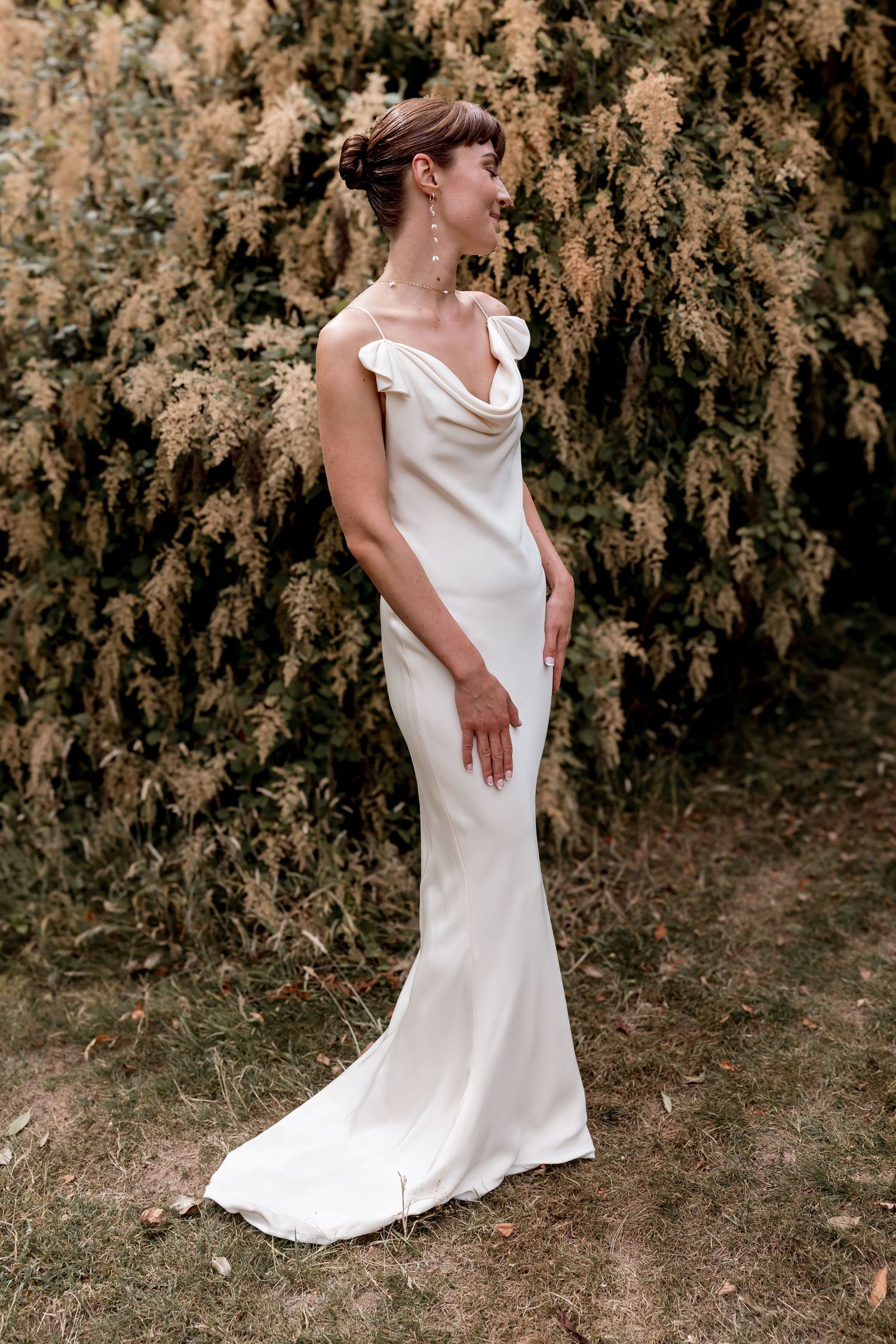 Elegant white wedding dress shown in multiple poses against a natural outdoor backdrop with autumn foliage.