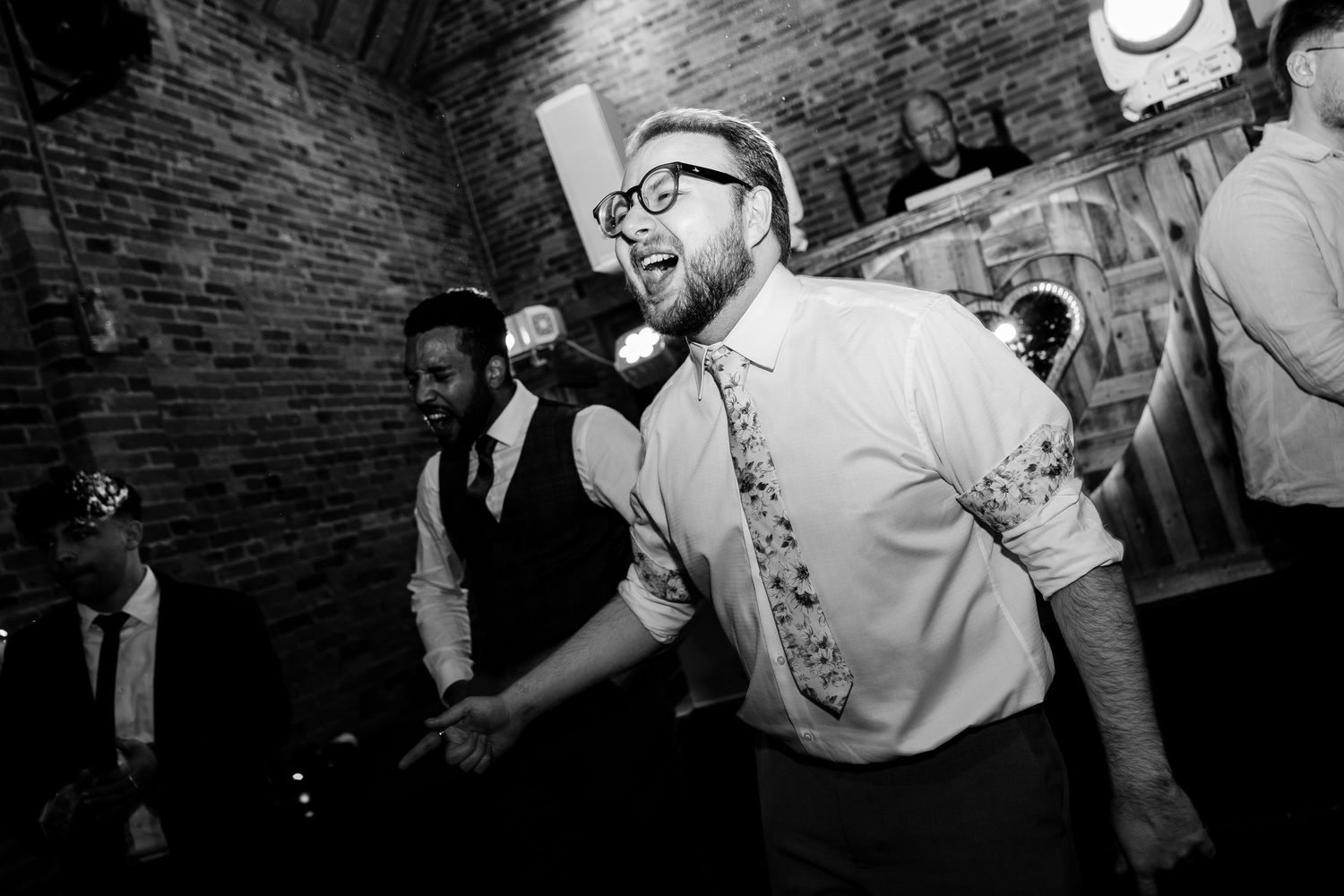 Black and white candid shot of wedding guest dancing enthusiastically at reception.
