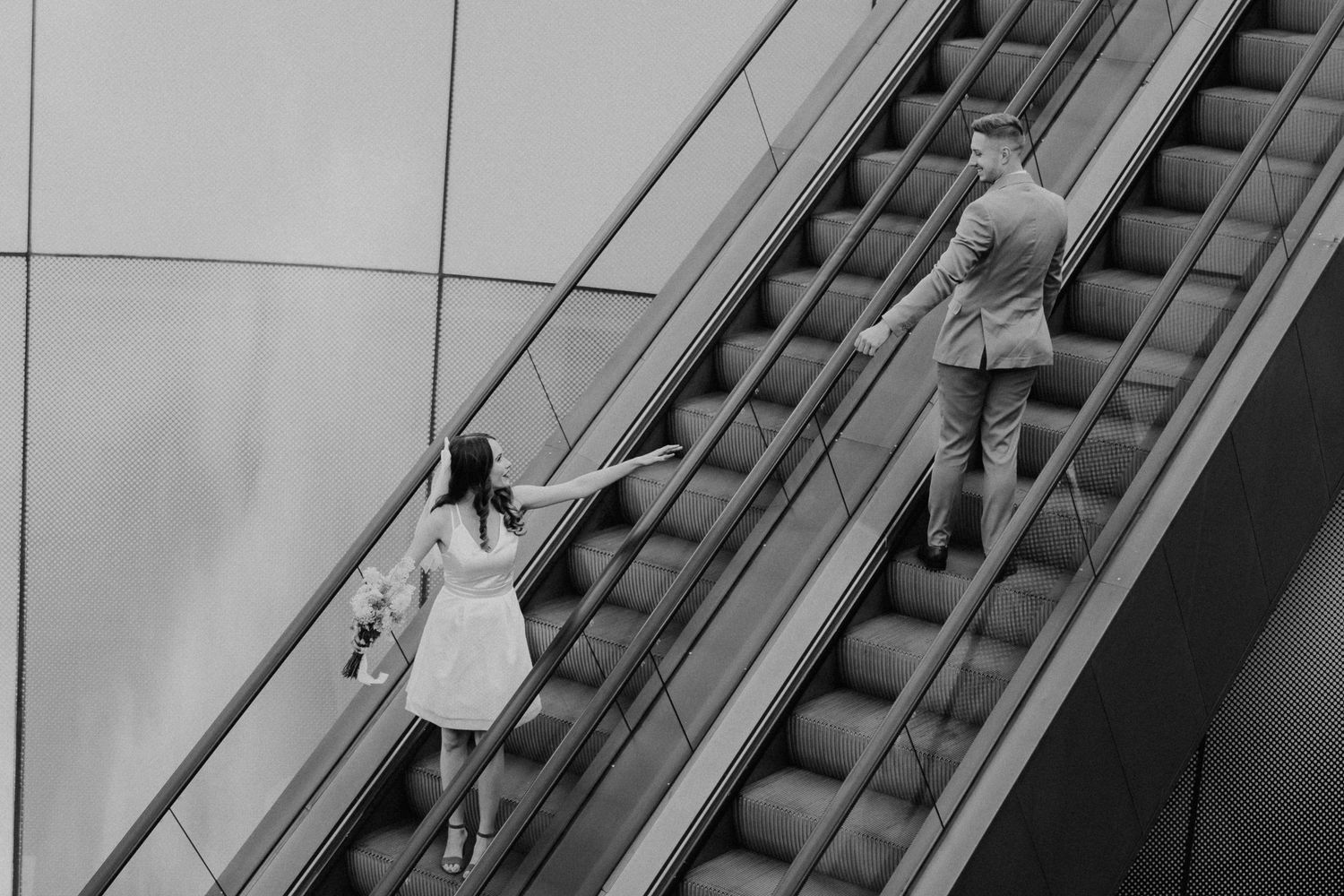 Brautpaar auf einer Rolltreppe in der Stadt in schwarz-weiß