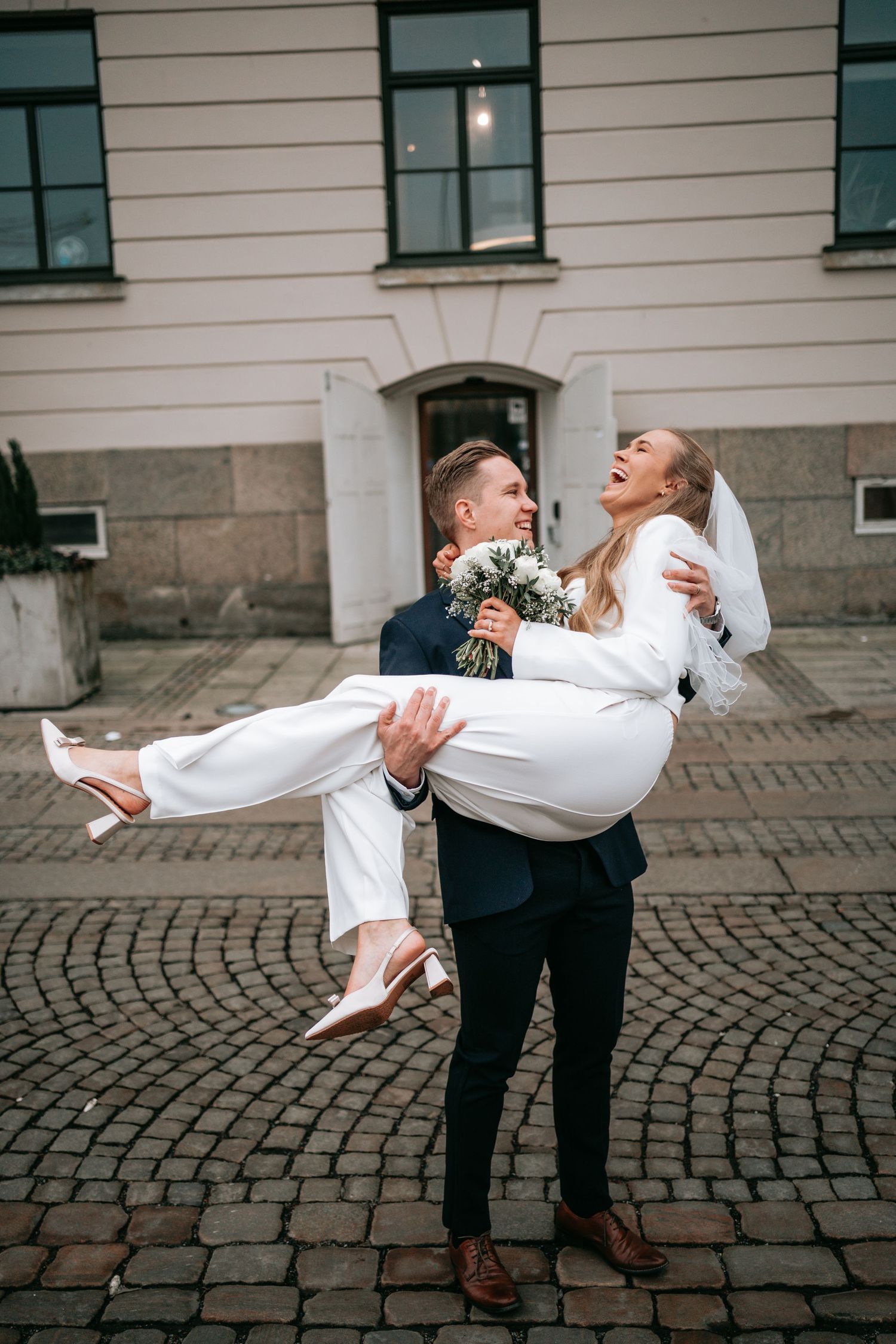 brudgum som bär sin brud utanför rådhuset i göteborg, bröllopsfotografering Emmalin Larsson, Göteborg och västkusten
